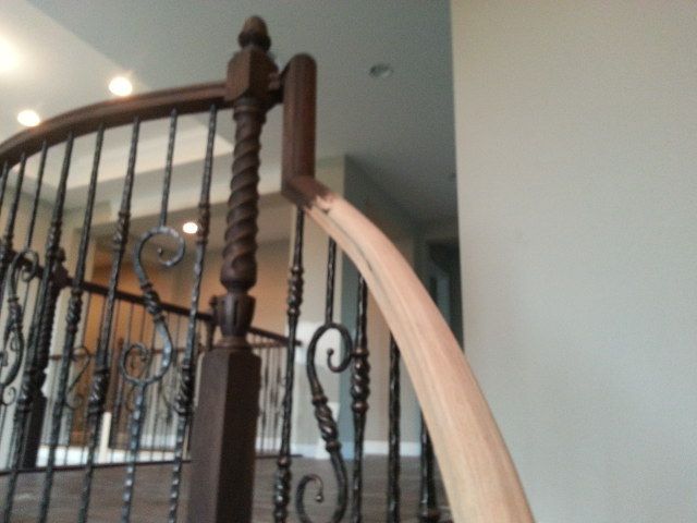 Curved wooden staircase with dark metal railing in a home interior