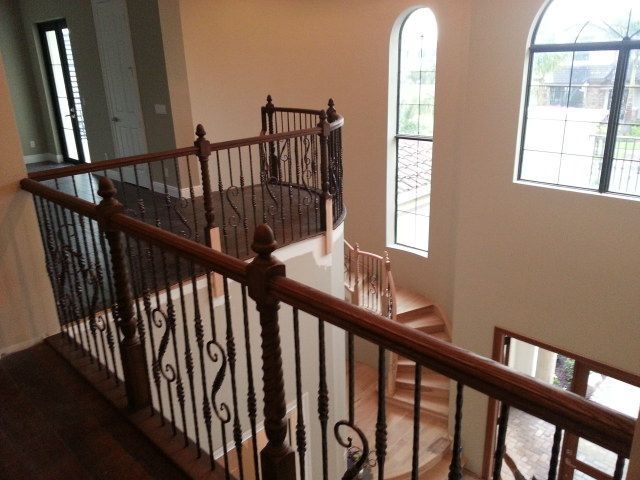 Interior view of a staircase landing with dark wood railing and large arched windows