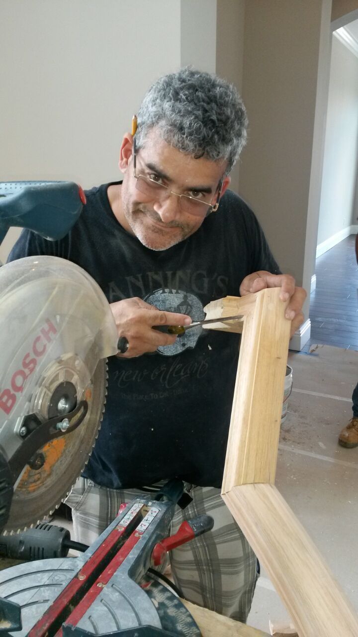 Man using a power drill to build a wooden frame indoors