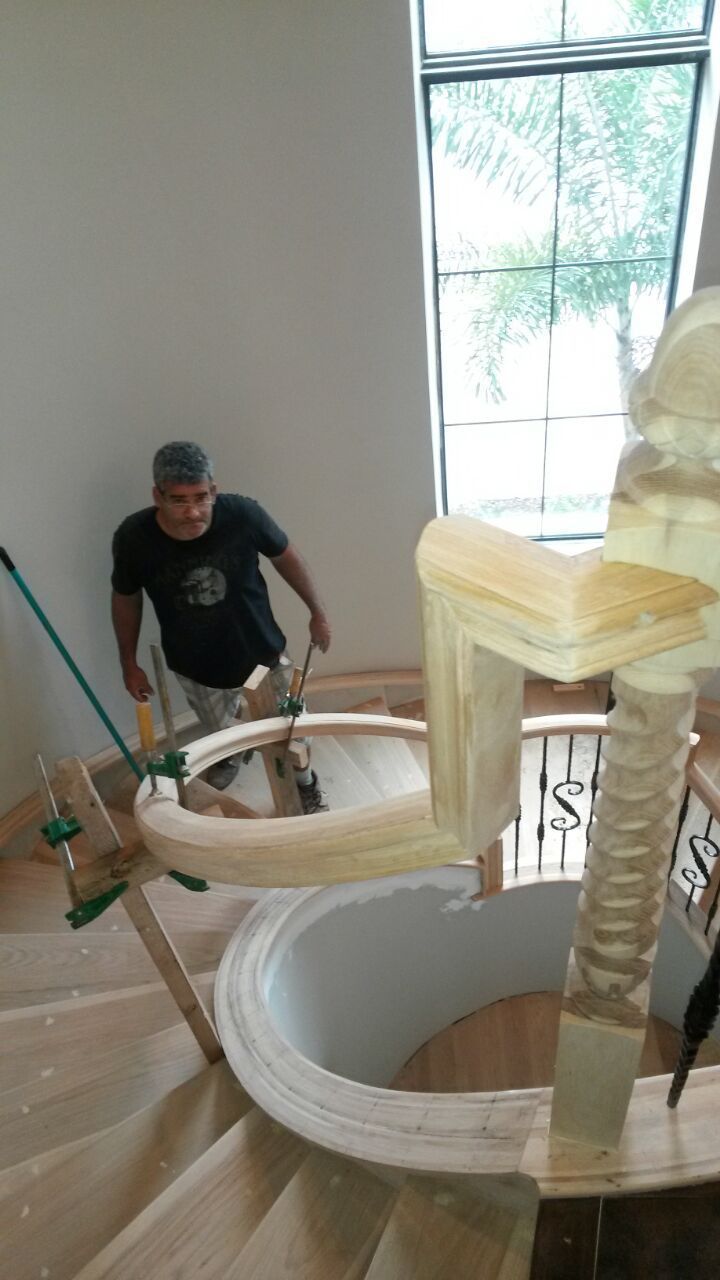 Man painting a large spiral staircase indoors near a window