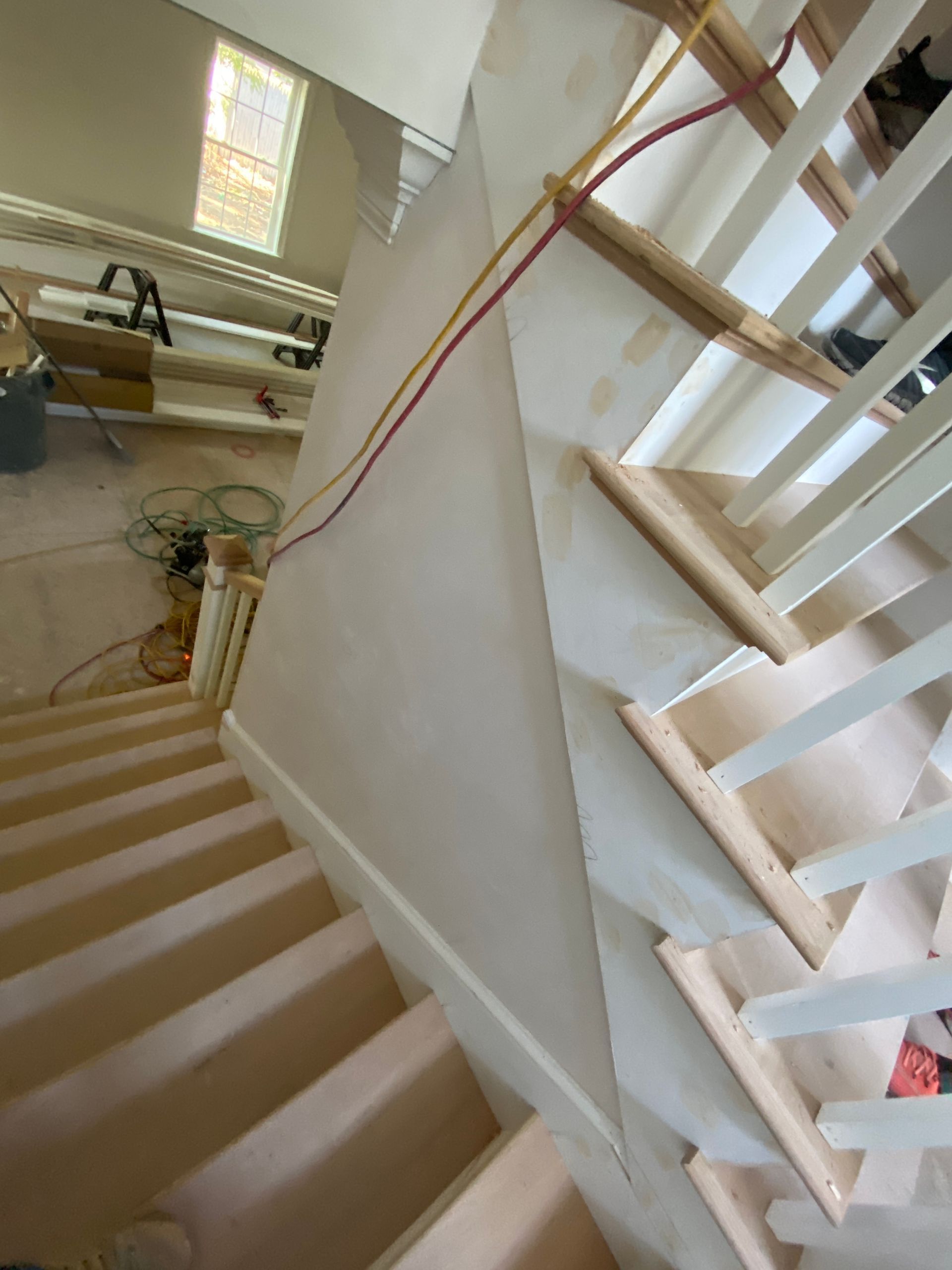 Stairwell with white railings, beige carpeted steps, and a skylight overhead
