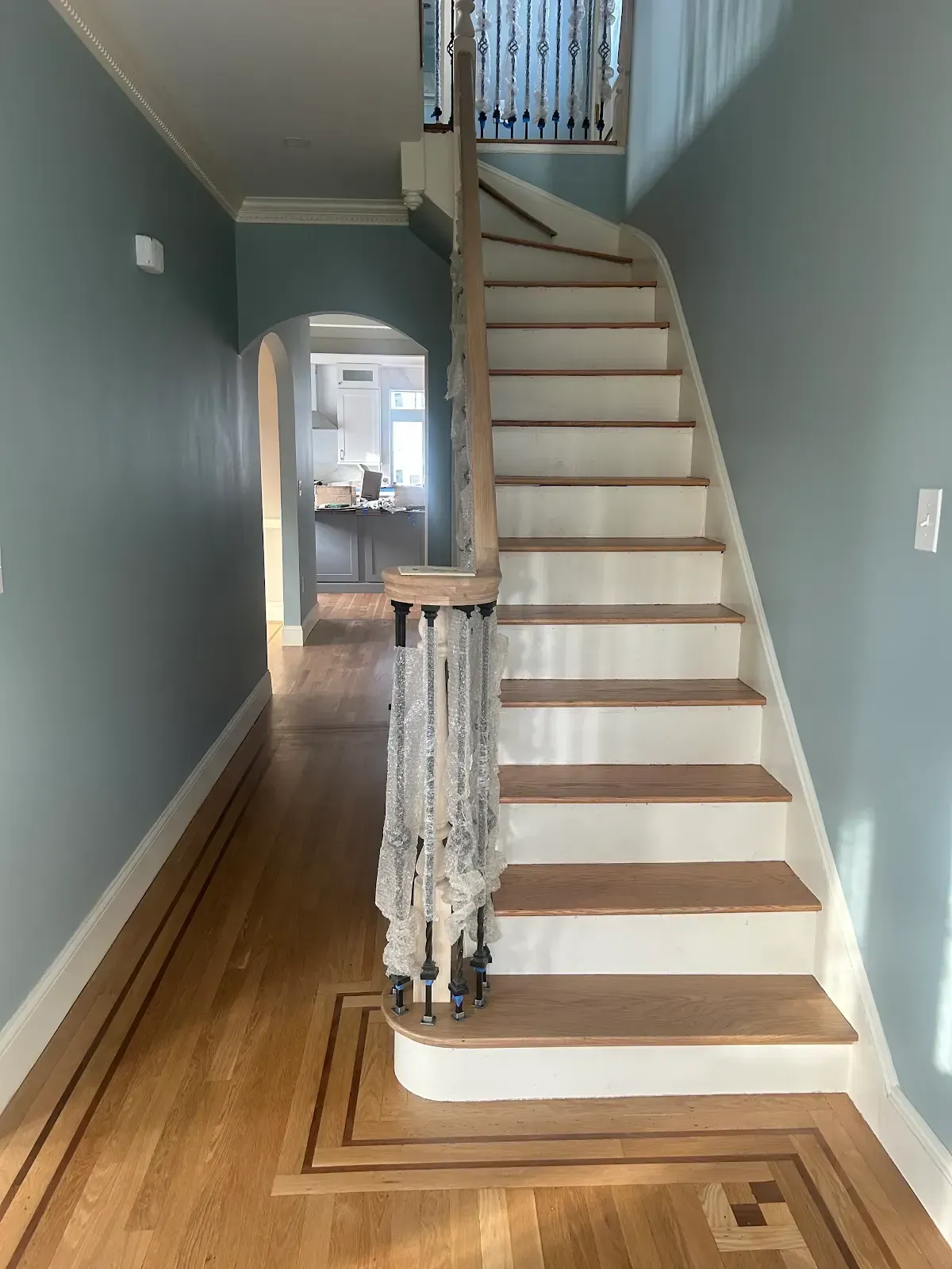 Narrow hallway with carpeted staircase, teal walls, white risers, and a small railing at the bottom.
