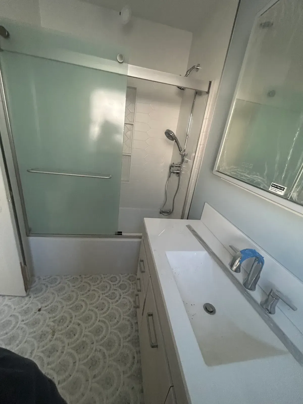 Small bathroom with tub, glass shower door, pedestal sink, and patterned tile floor