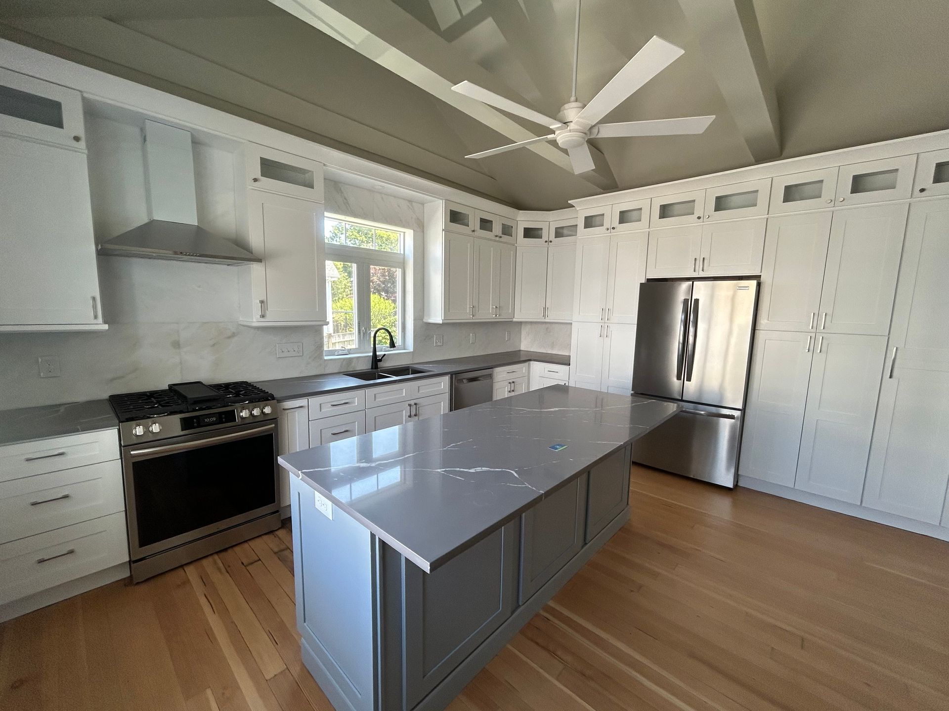Bright modern kitchen with white cabinets, stainless appliances, and a large gray island.