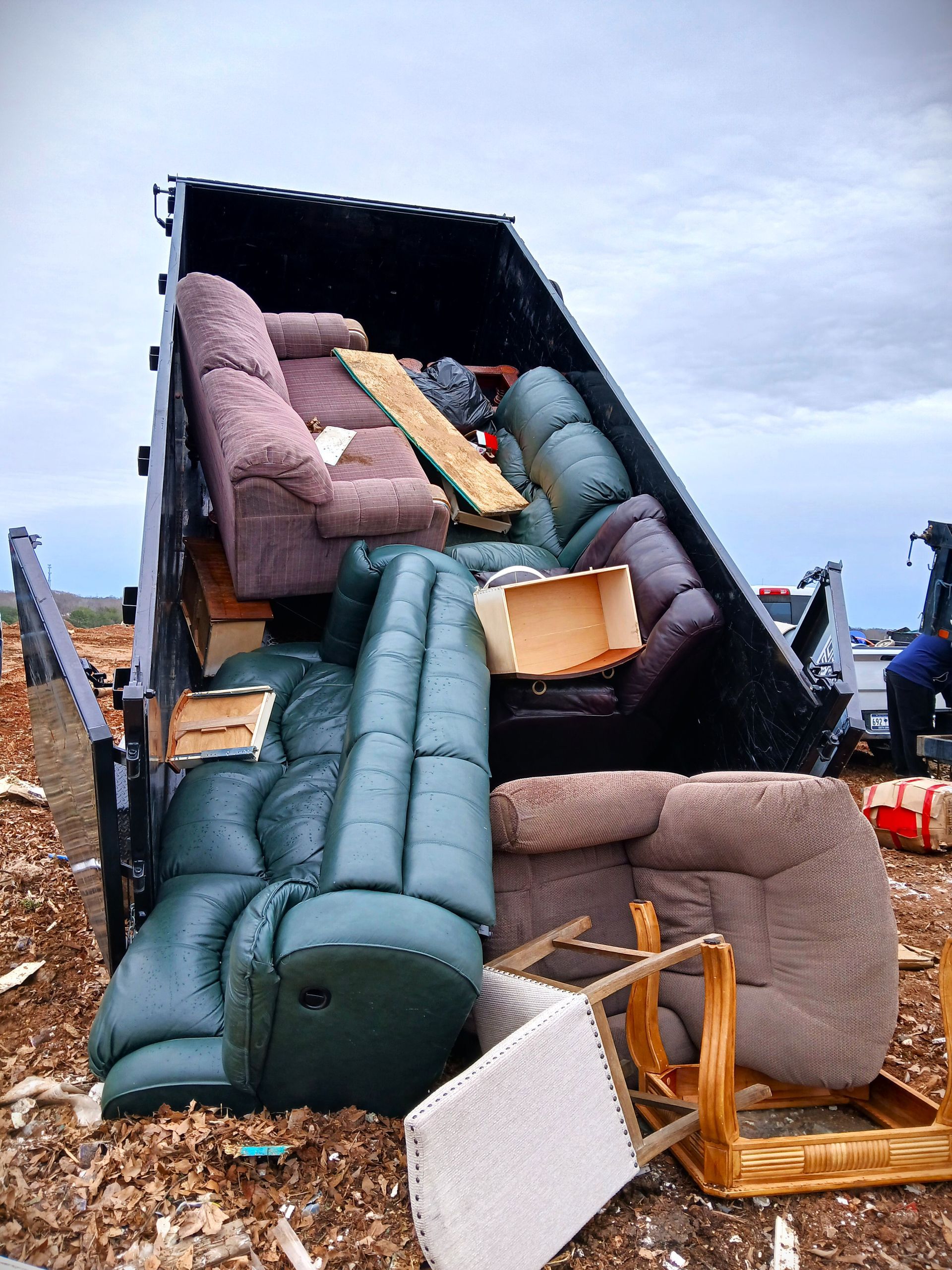 Overturned truck spilled furniture and household items onto a roadside area.