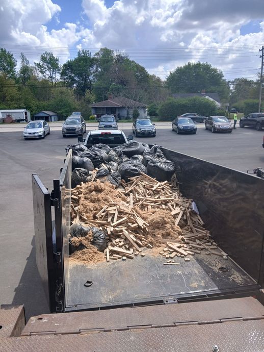 Dumpster filled with wood debris in a parking lot on a cloudy day