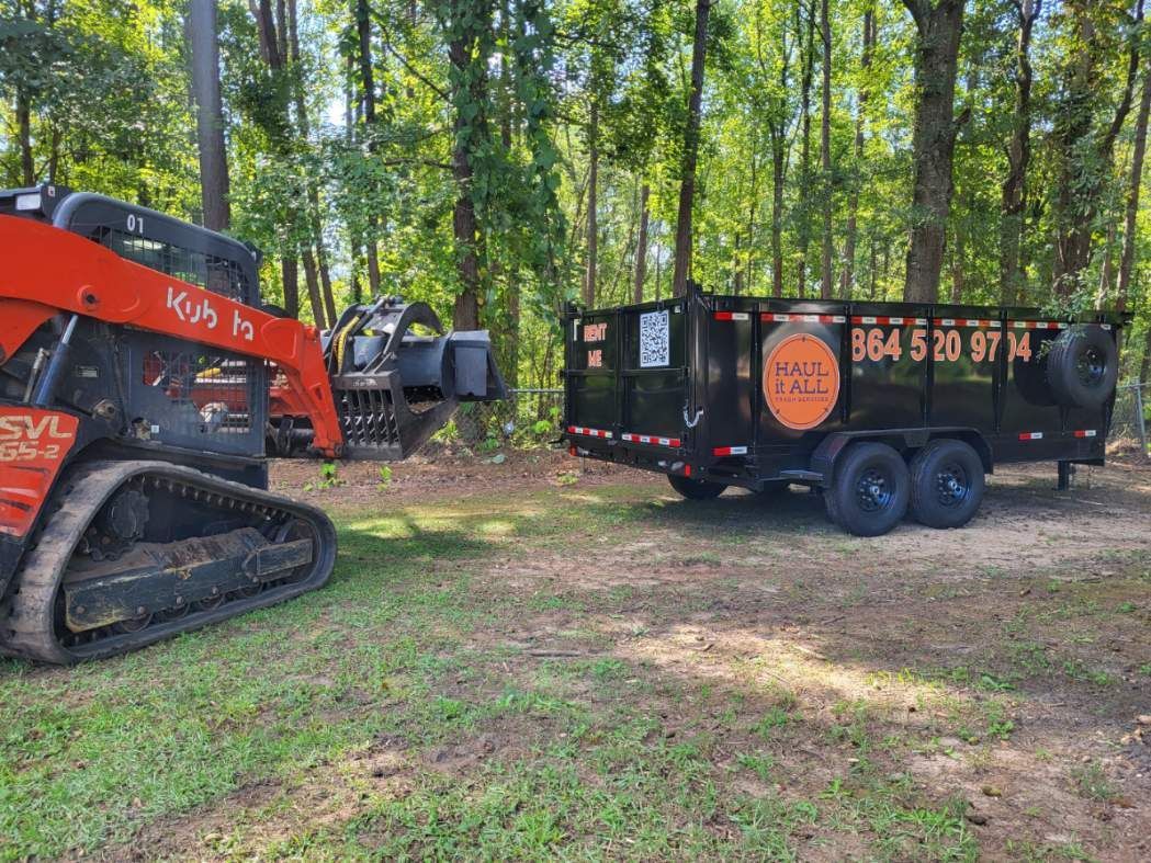 Orange excavator beside black dumpster trailer in a wooded clearing