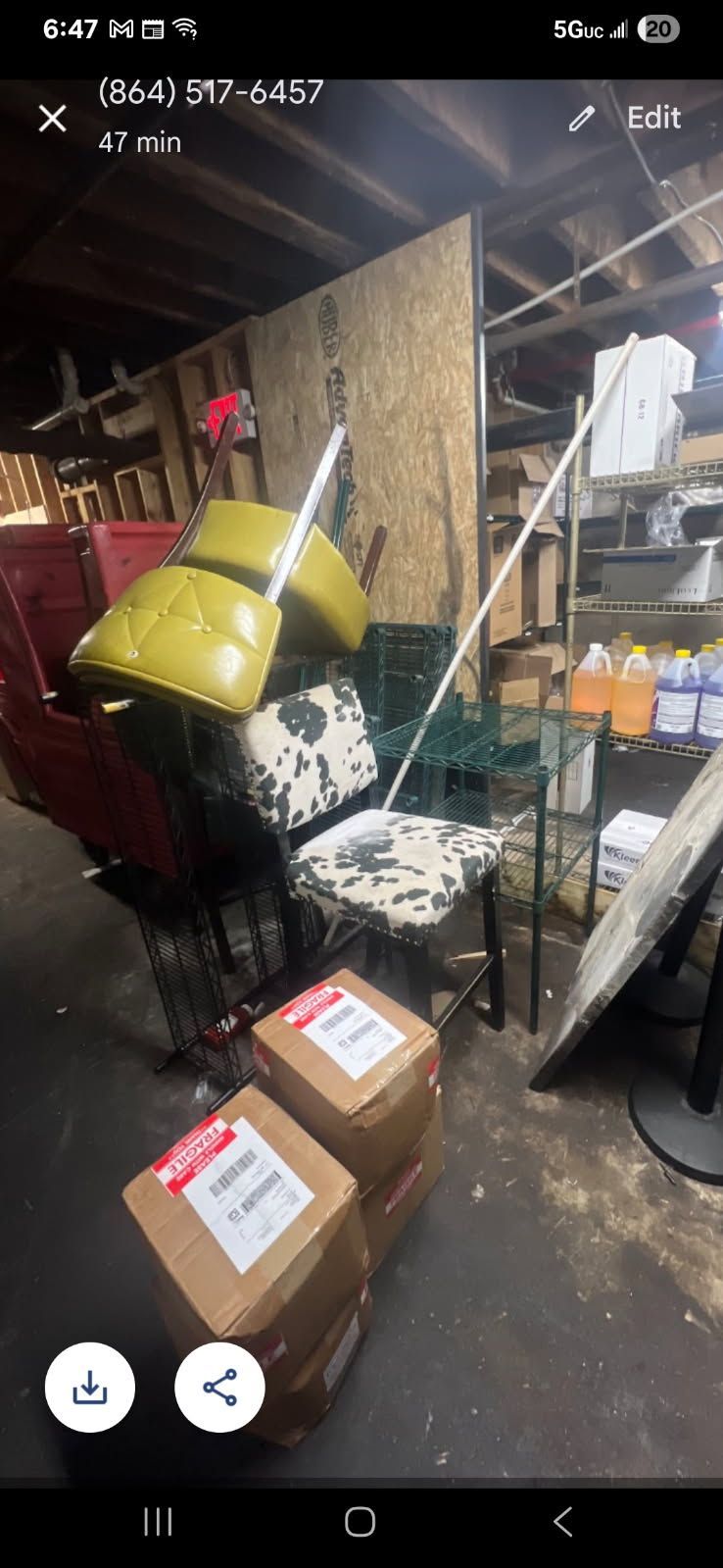Cluttered storage area with boxes, a tipped yellow chair, shelving, and hanging tools.