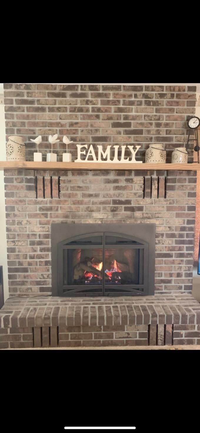 Brick fireplace with a lit fire and a “FAMILY” mantel sign above it.