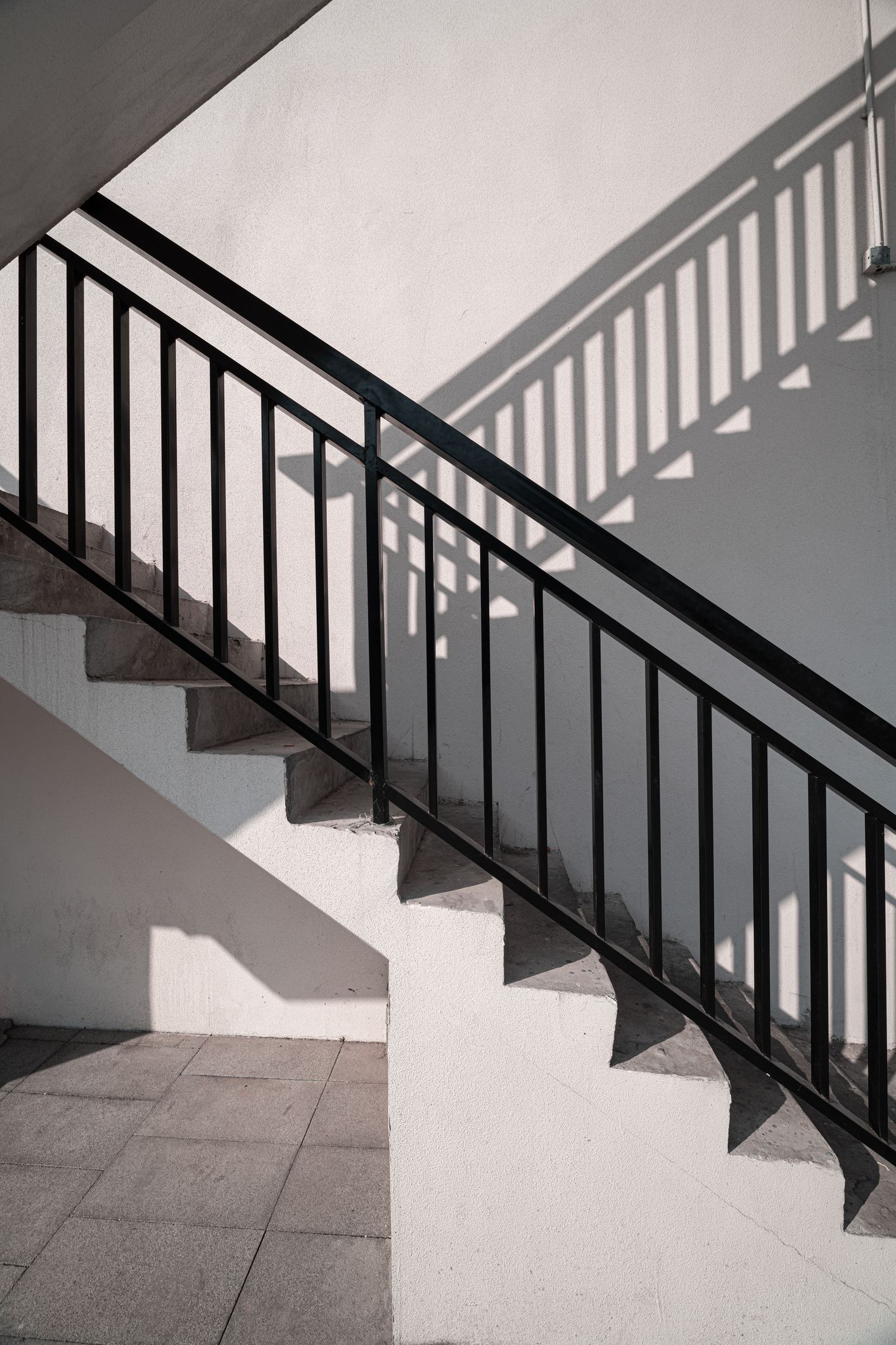 A staircase with a black railing and a shadow on the wall.