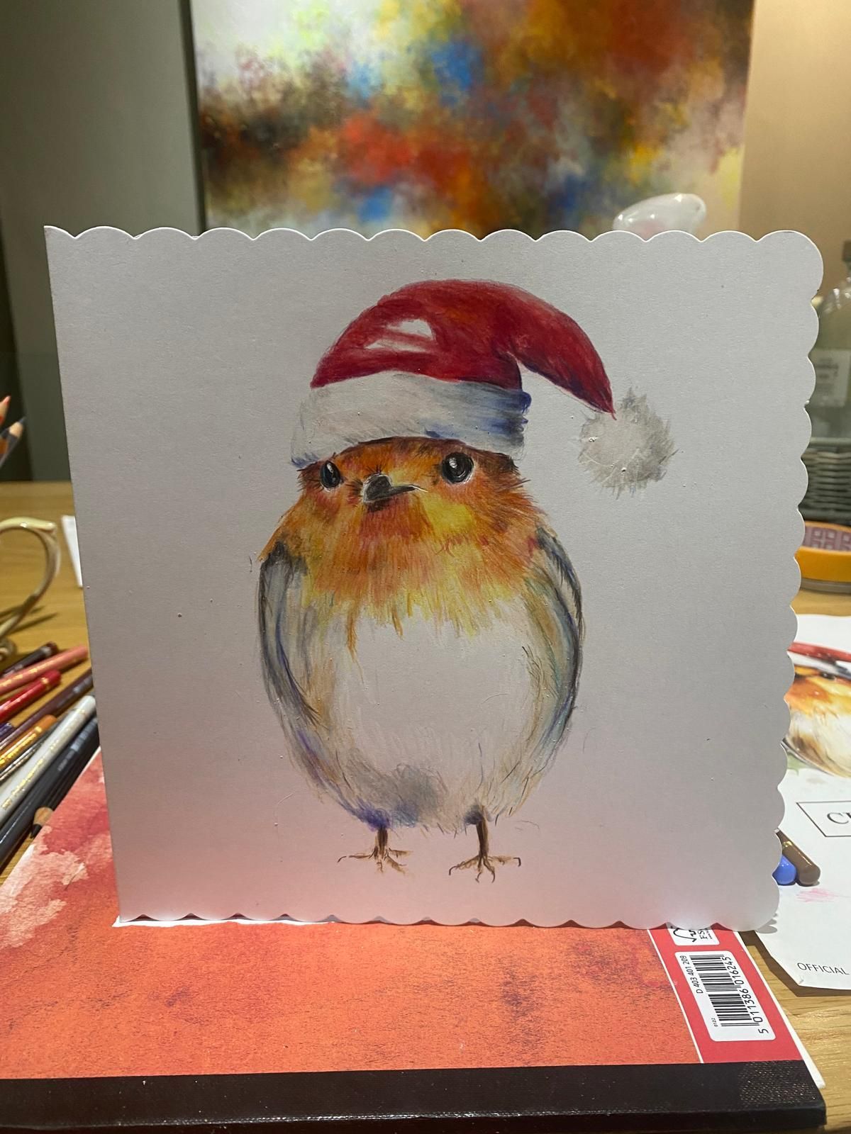 Christmas card with watercolor painting of a robin wearing a Santa hat.