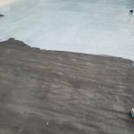 A roof partially painted light gray, contrasting with the dark gray unfinished section.