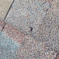 Close-up of weathered asphalt roof shingles with various colors, showing texture.