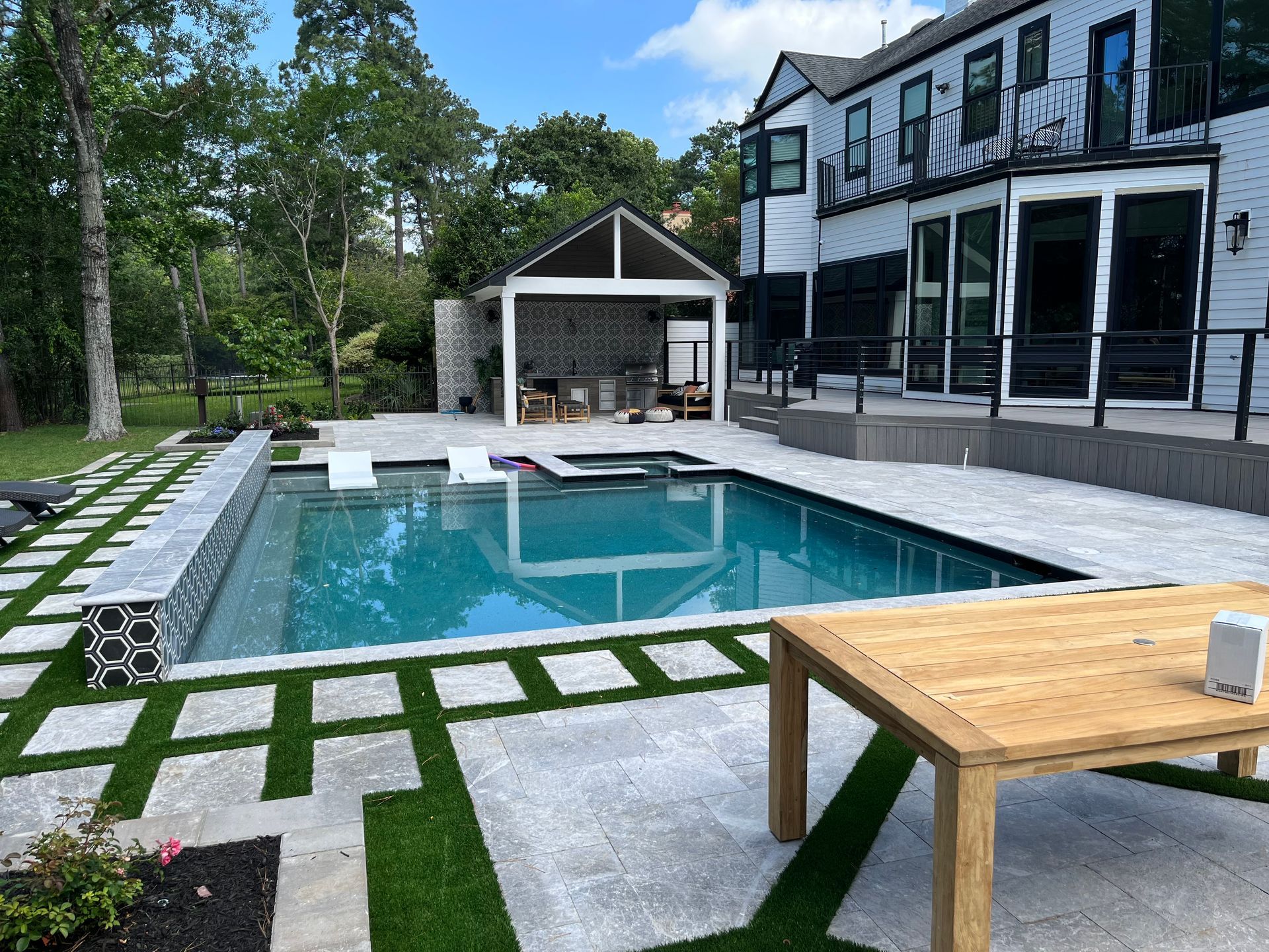 There is a large swimming pool in the backyard of a house.