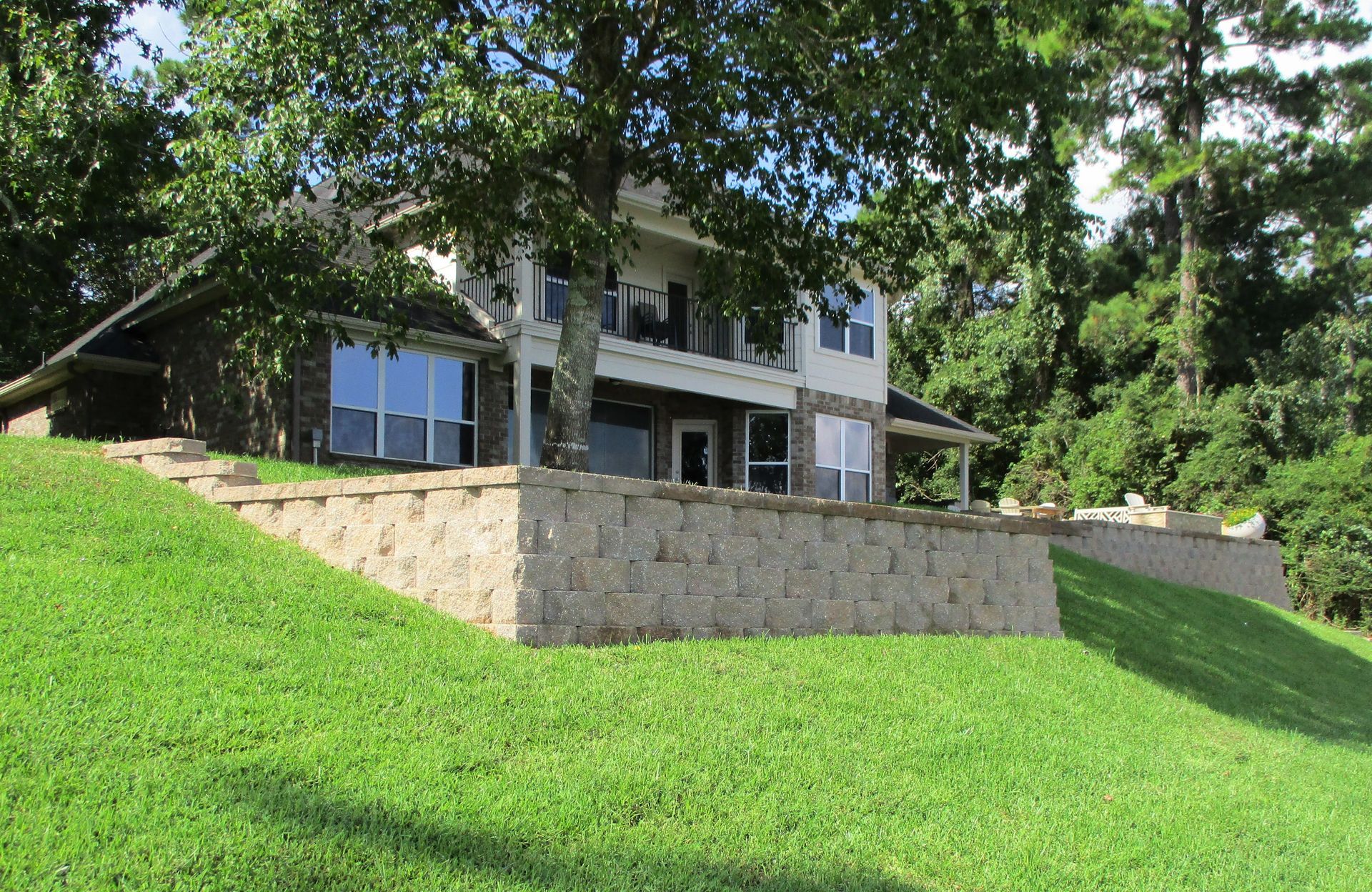 A large house is sitting on top of a lush green hill.