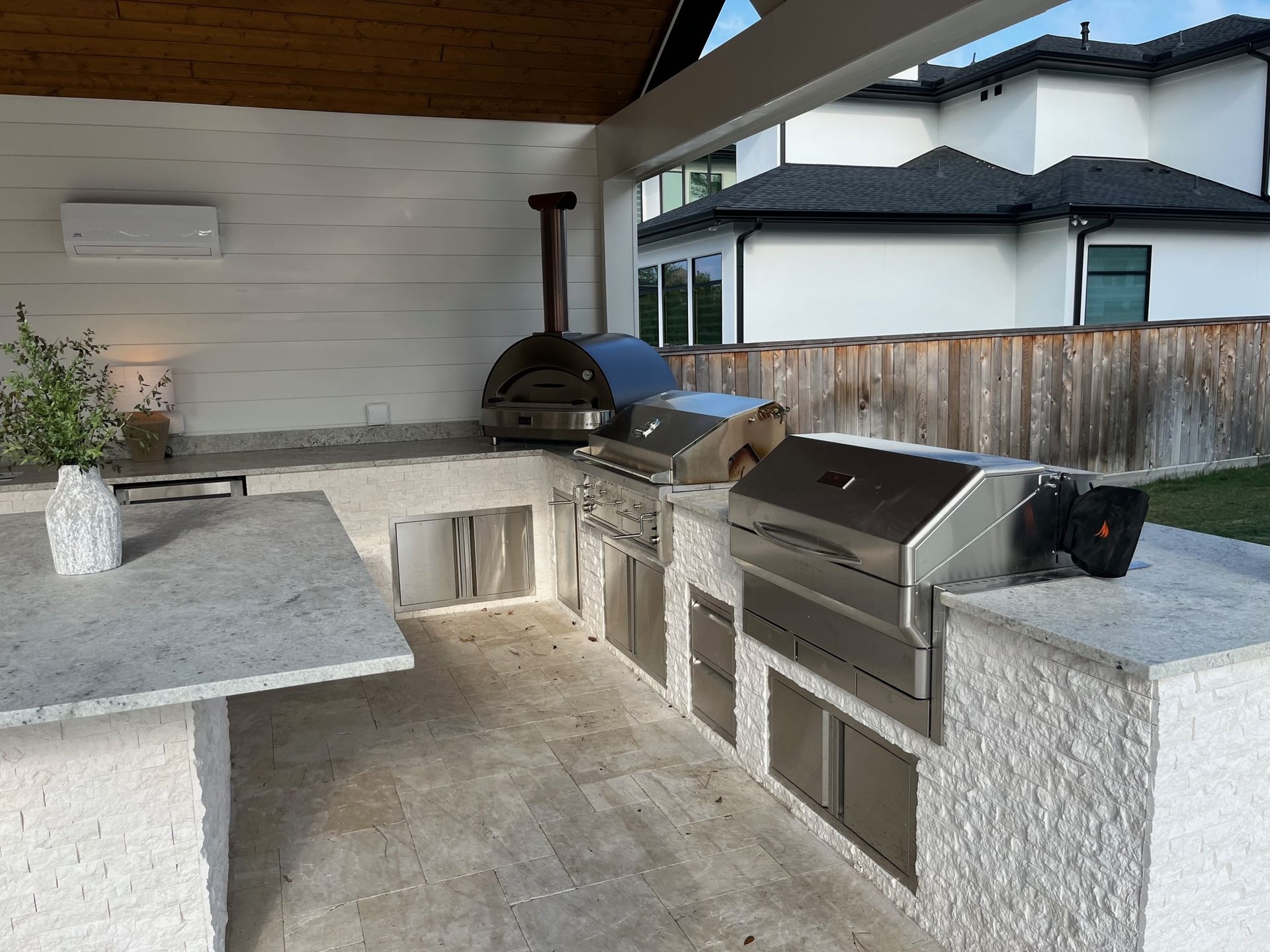 A large outdoor kitchen with a grill and a pizza oven.