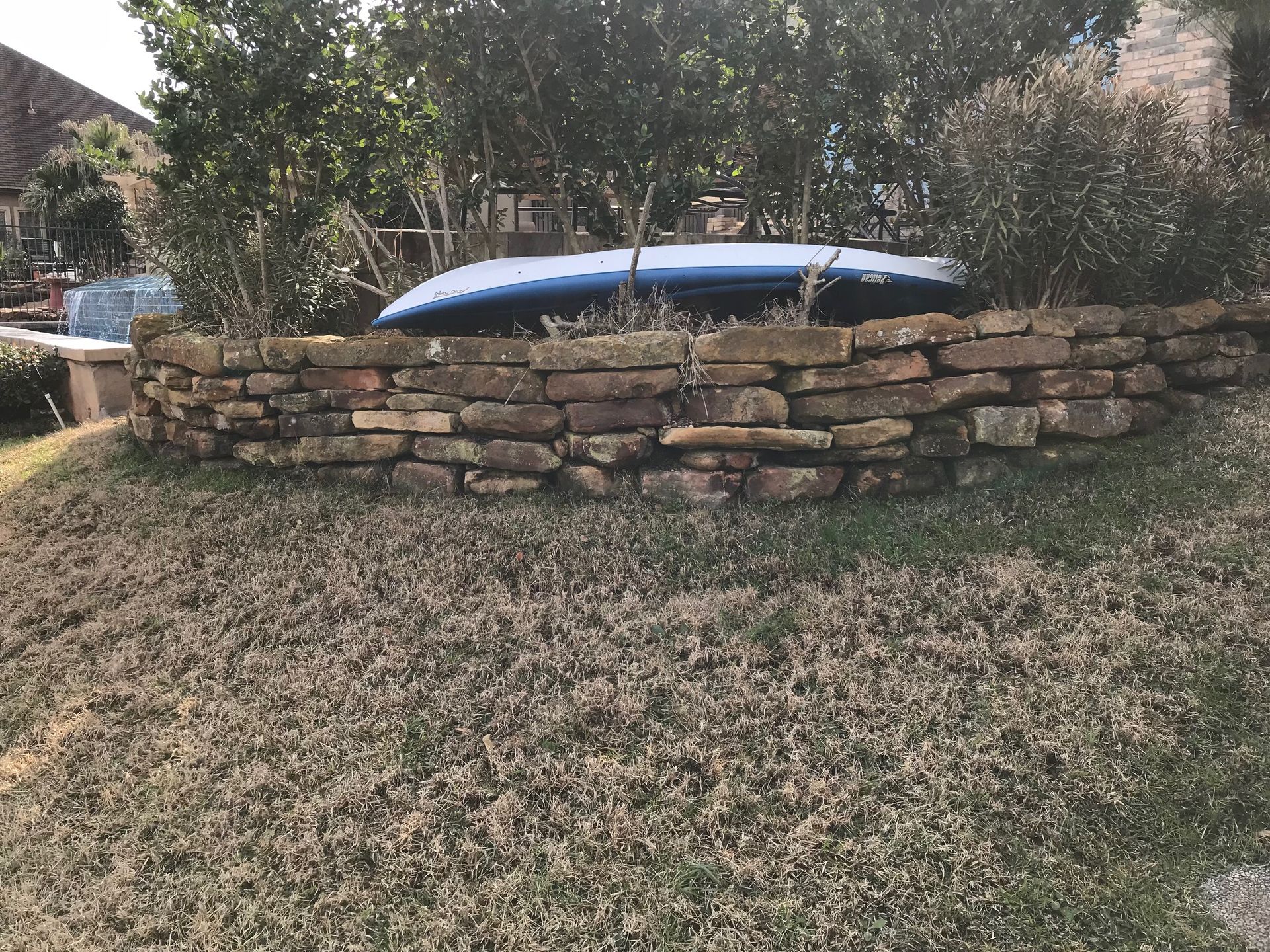 A blue surfboard is sitting on top of a stone wall.