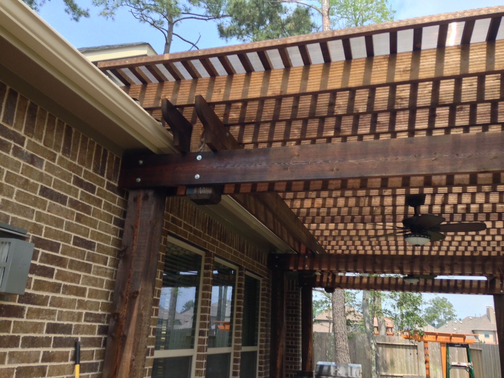 A brick house with a wooden pergola and a ceiling fan
