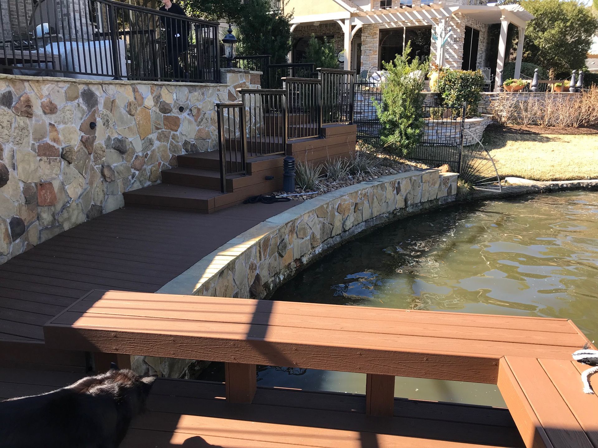 A wooden bench is sitting next to a stone wall next to a body of water.