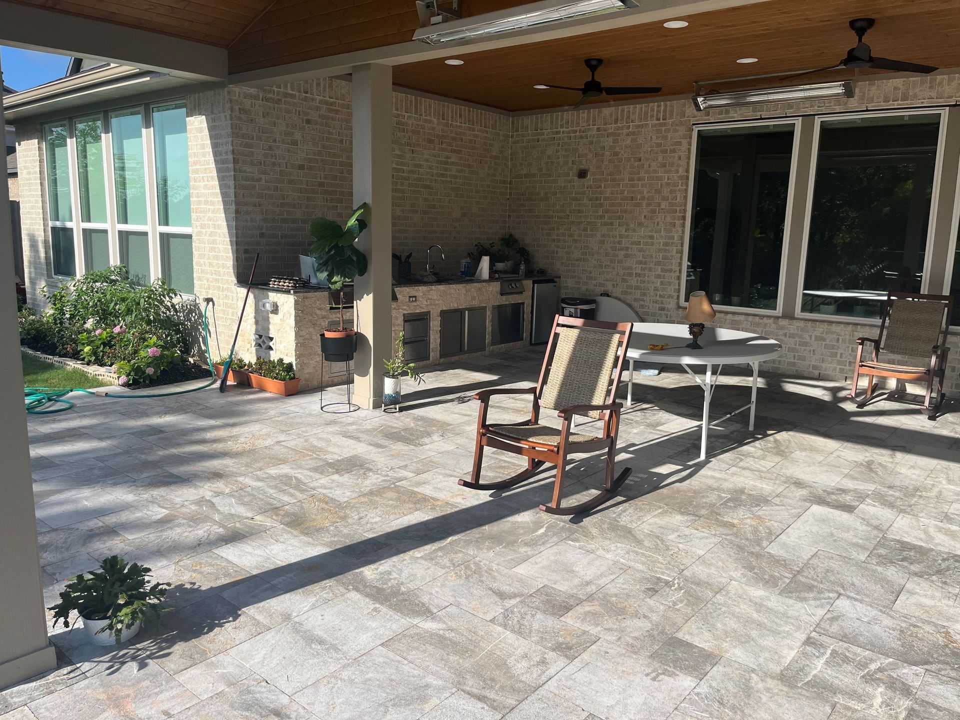 A patio with rocking chairs , a table and a ceiling fan.