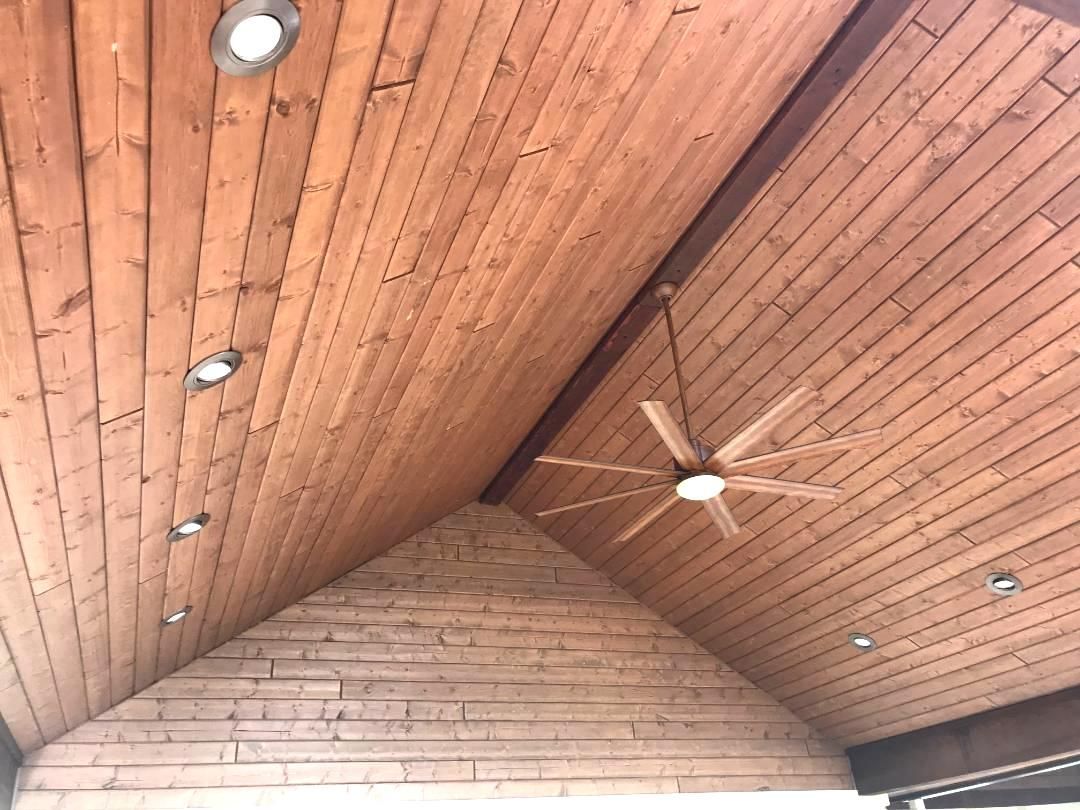 A wooden ceiling with a ceiling fan hanging from it