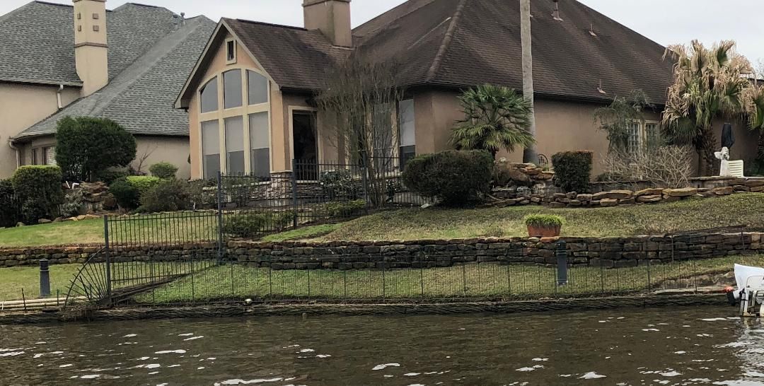 A large house is sitting on top of a hill next to a body of water.
