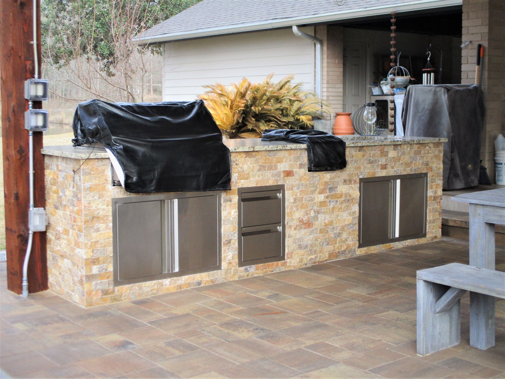 An outdoor kitchen with a grill and a table and benches