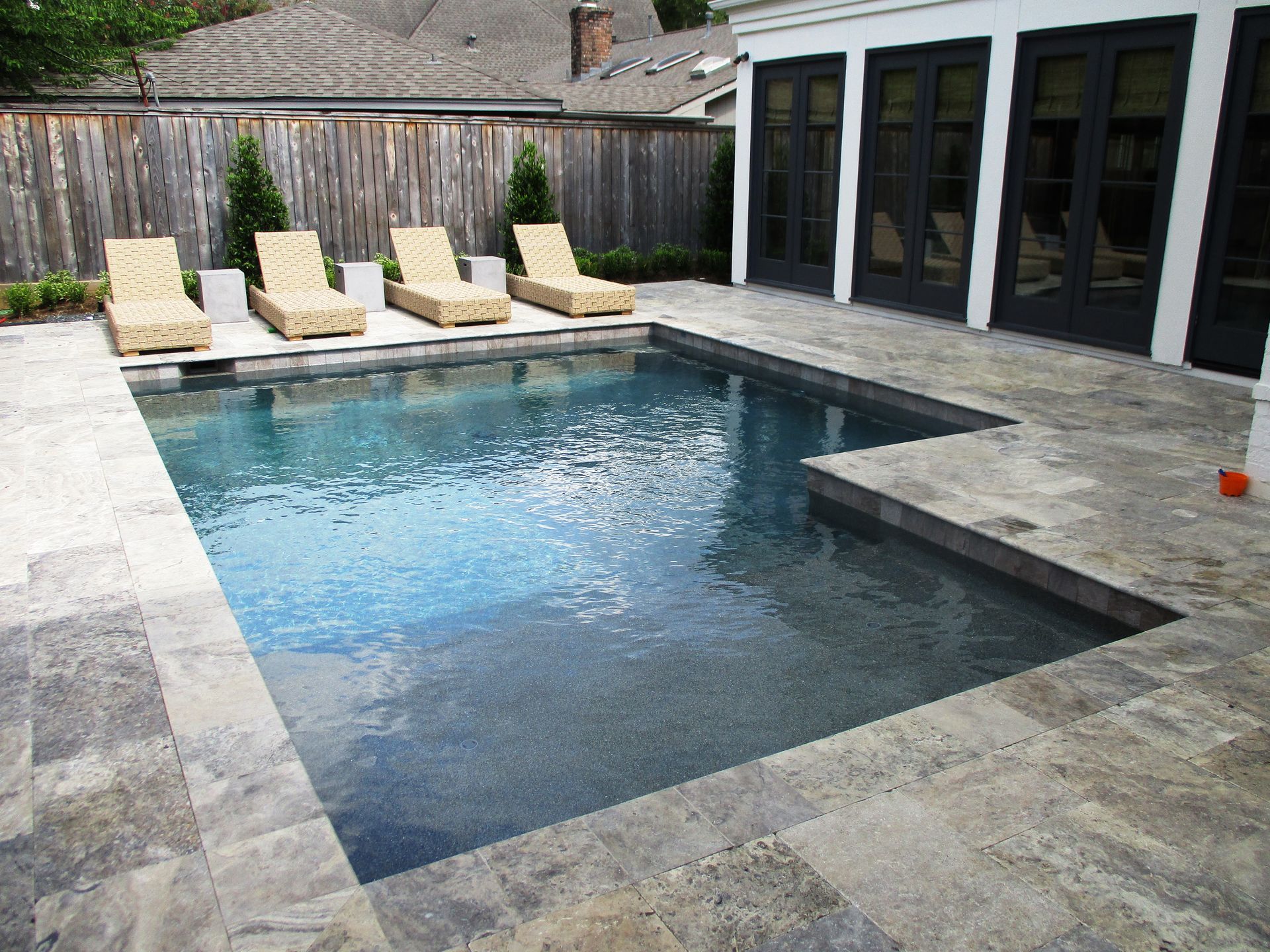 A large swimming pool surrounded by chairs and a fence