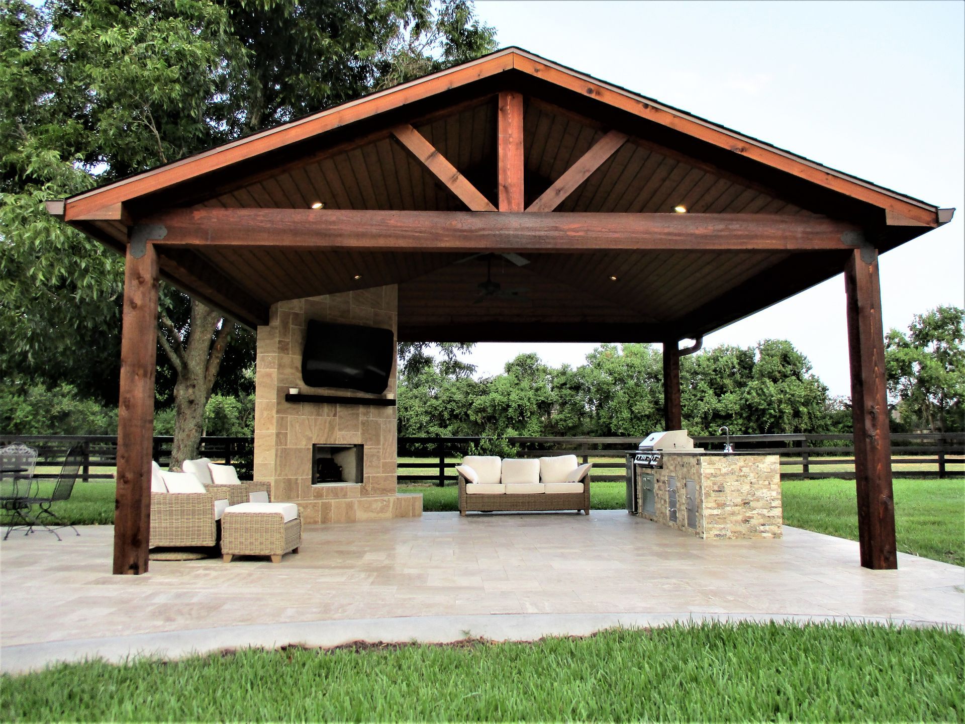 A large wooden pavilion with a fireplace and a couch underneath it