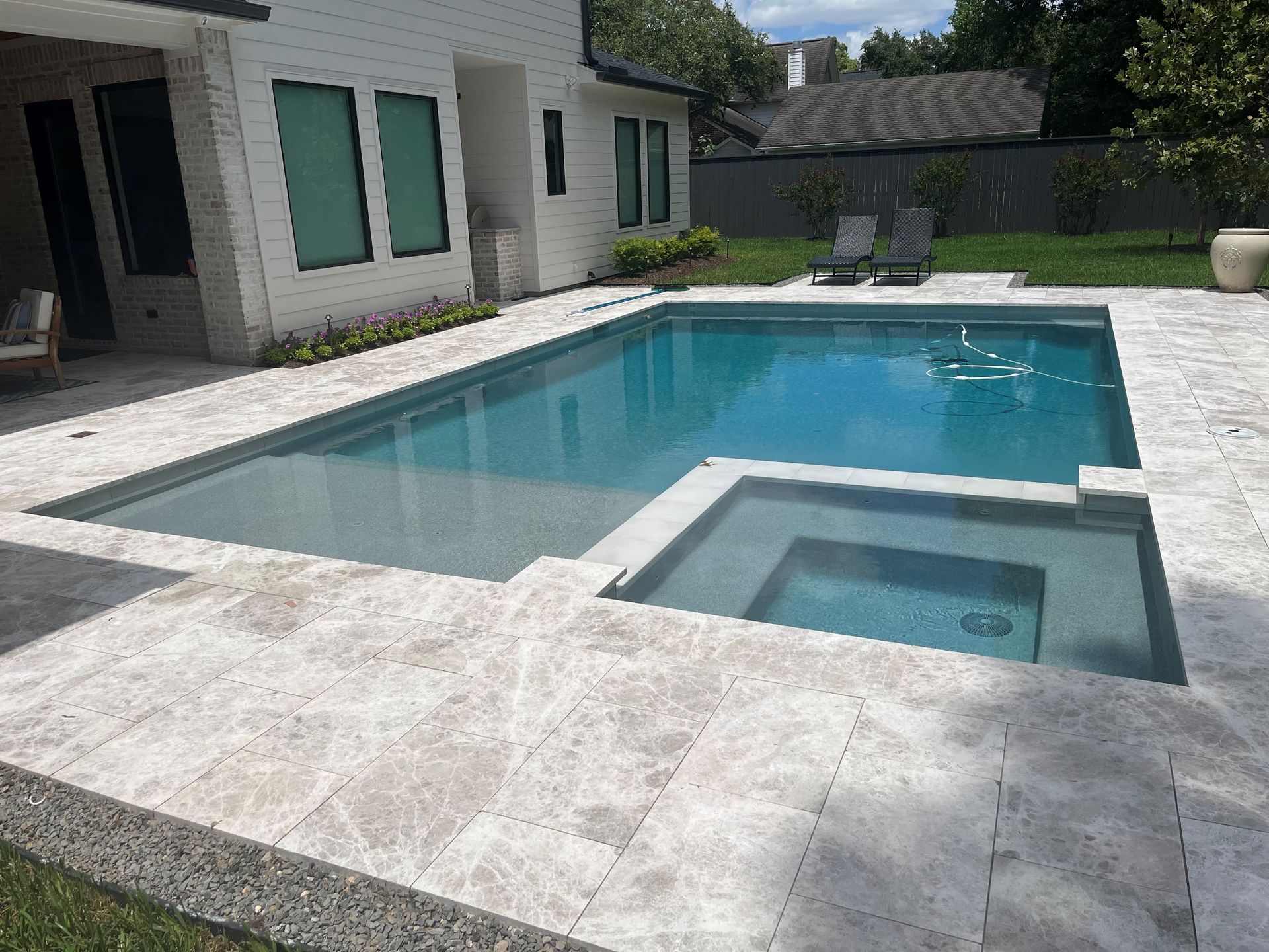 There is a large swimming pool in the backyard of a house.