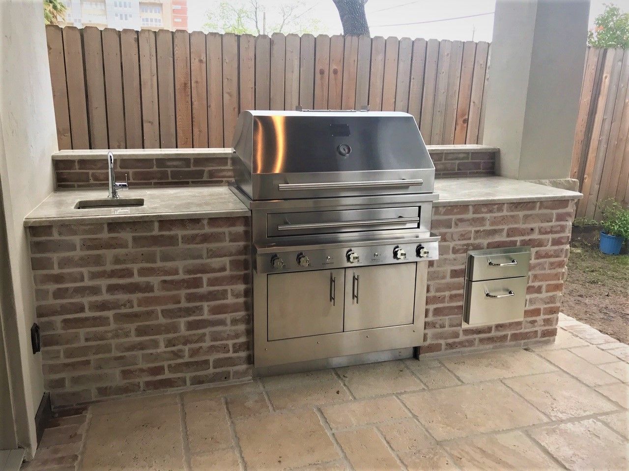 A stainless steel grill is built into a brick wall.