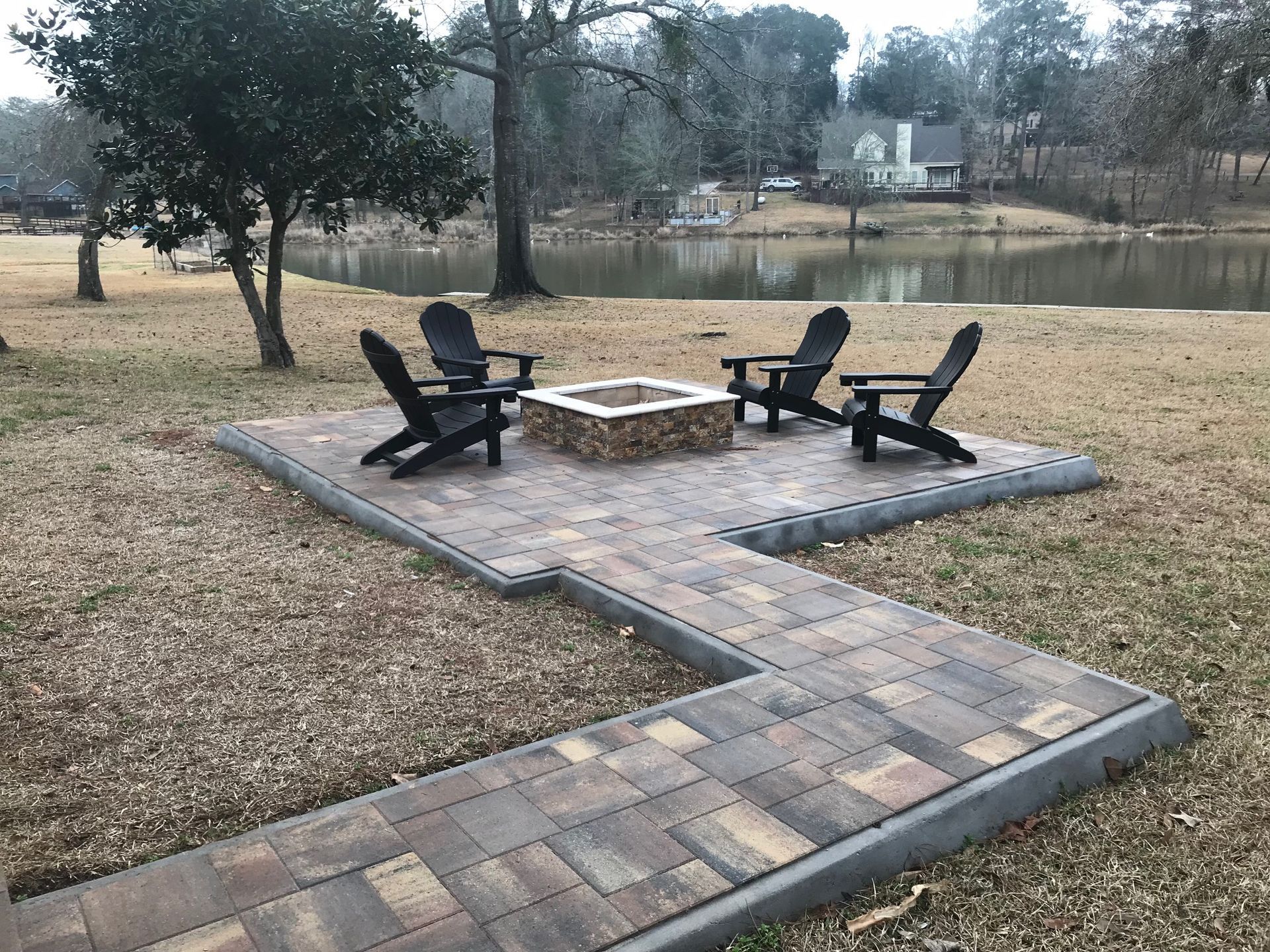 A fire pit with chairs in front of a lake.