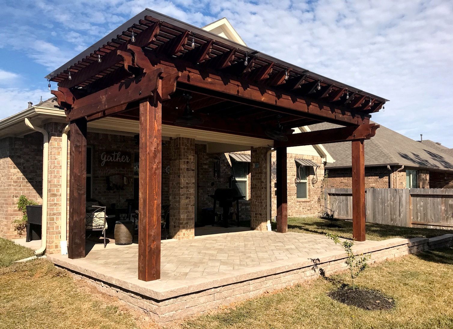 A wooden pergola is sitting in the backyard of a house.