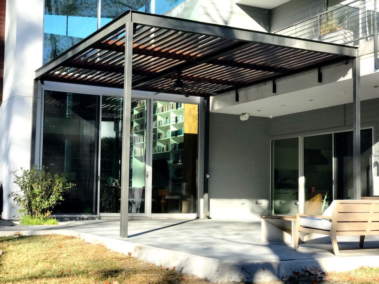 A patio with a pergola and chairs in front of a house