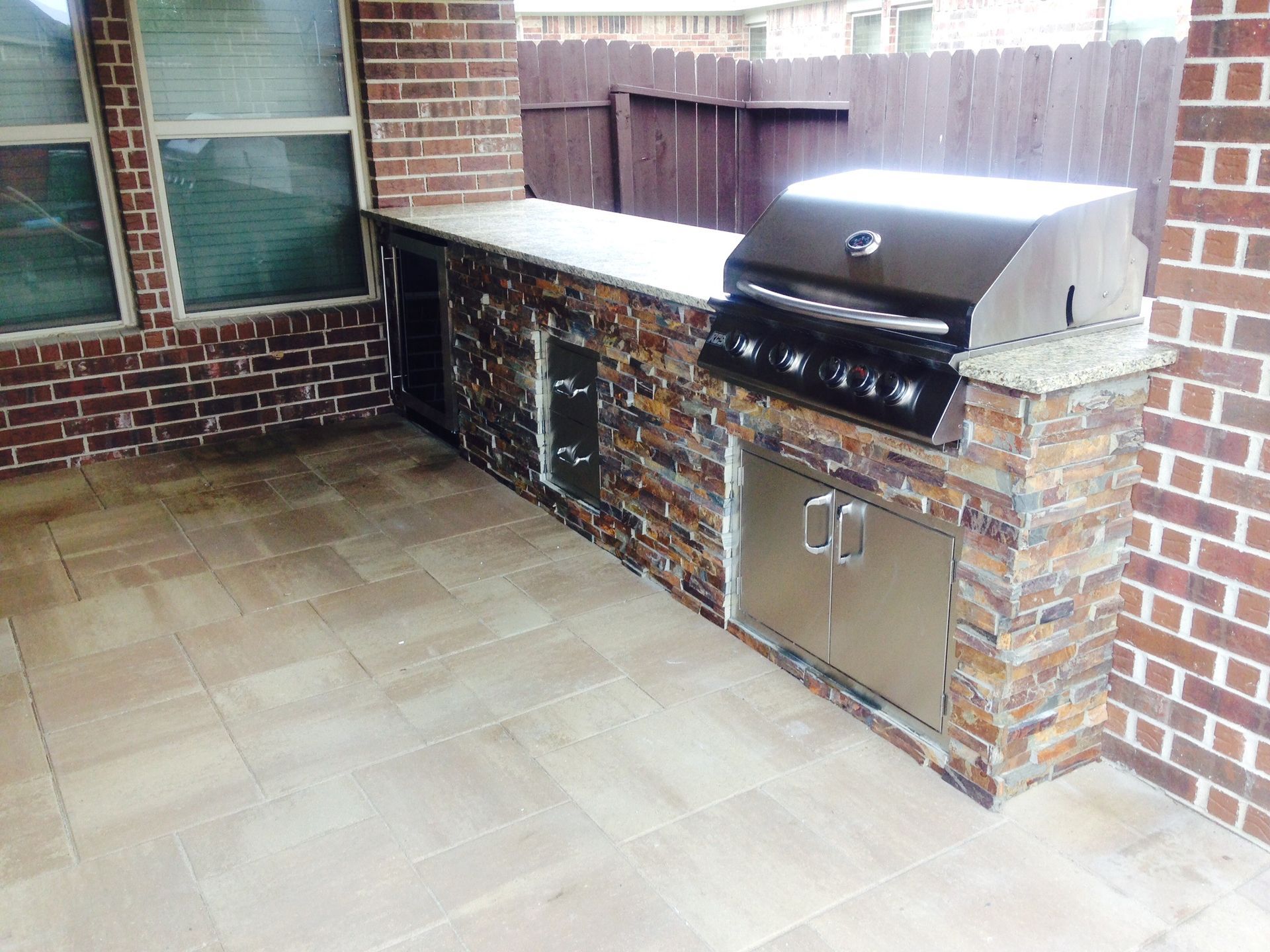 An outdoor kitchen with a grill and a brick wall