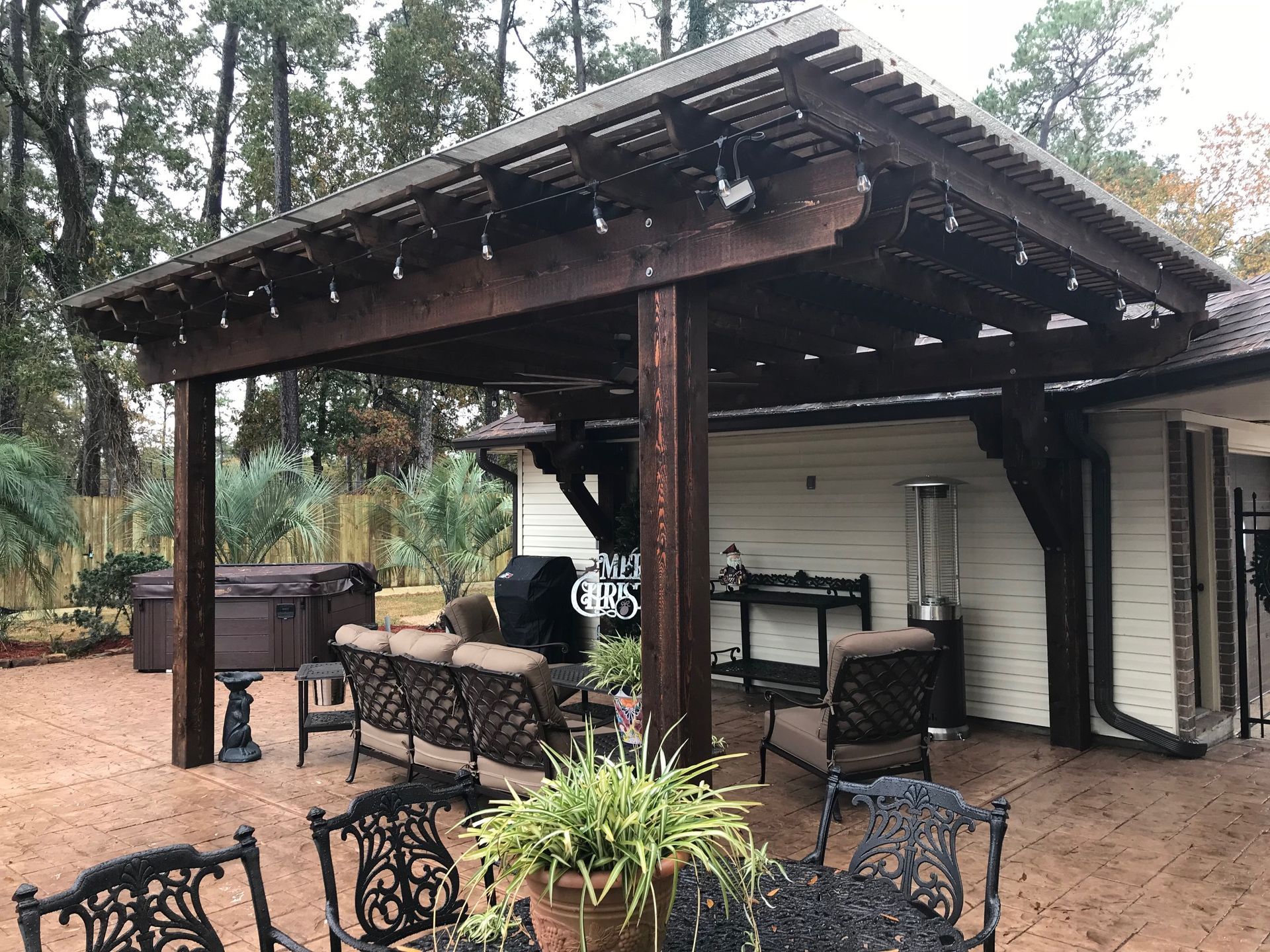 A wooden pergola with a table and chairs underneath it.