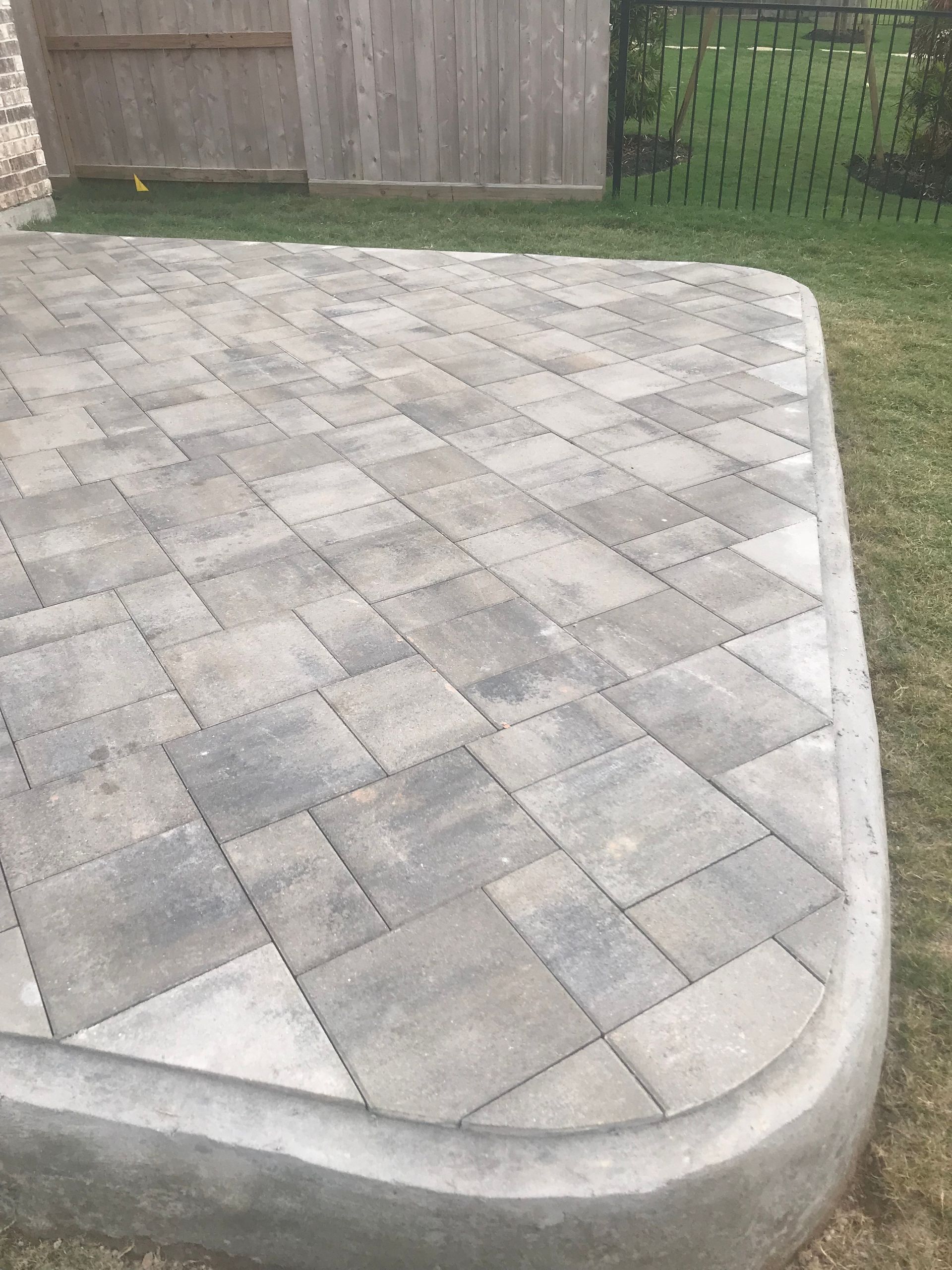 A patio with a concrete curb and a wooden fence in the background.