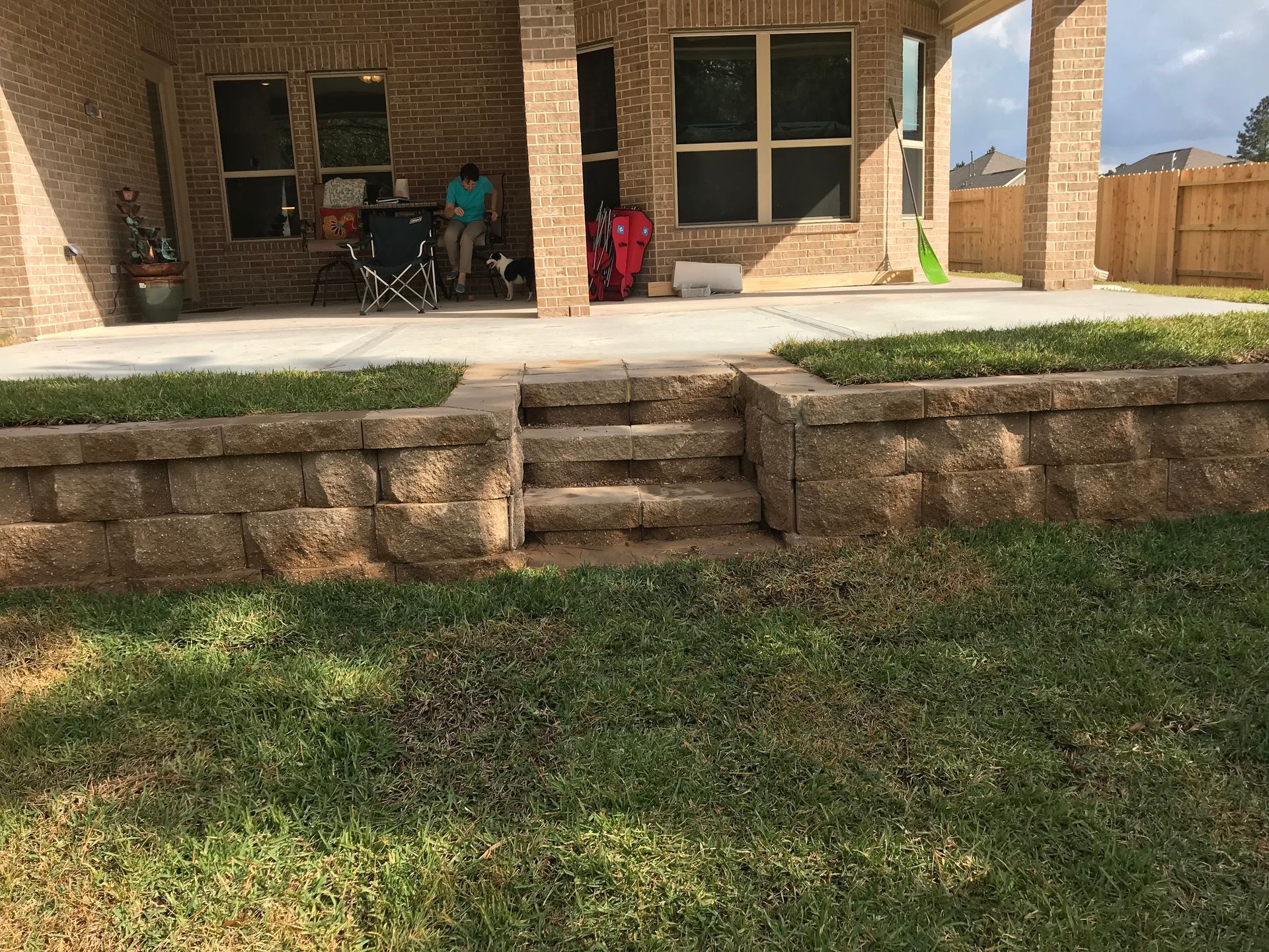 A family is sitting on the porch of a brick house.
