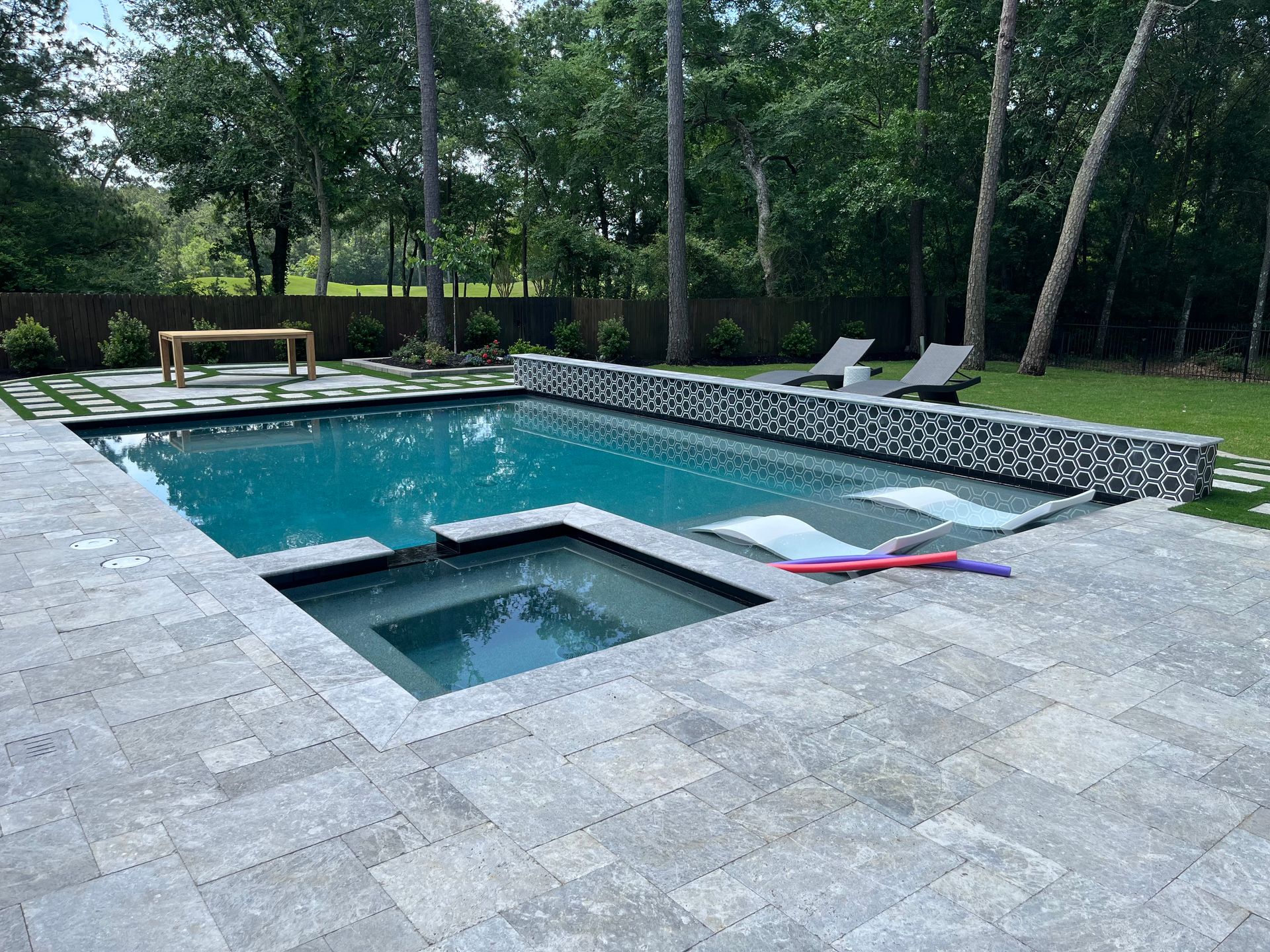 There is a large swimming pool with a hot tub in the middle of it.