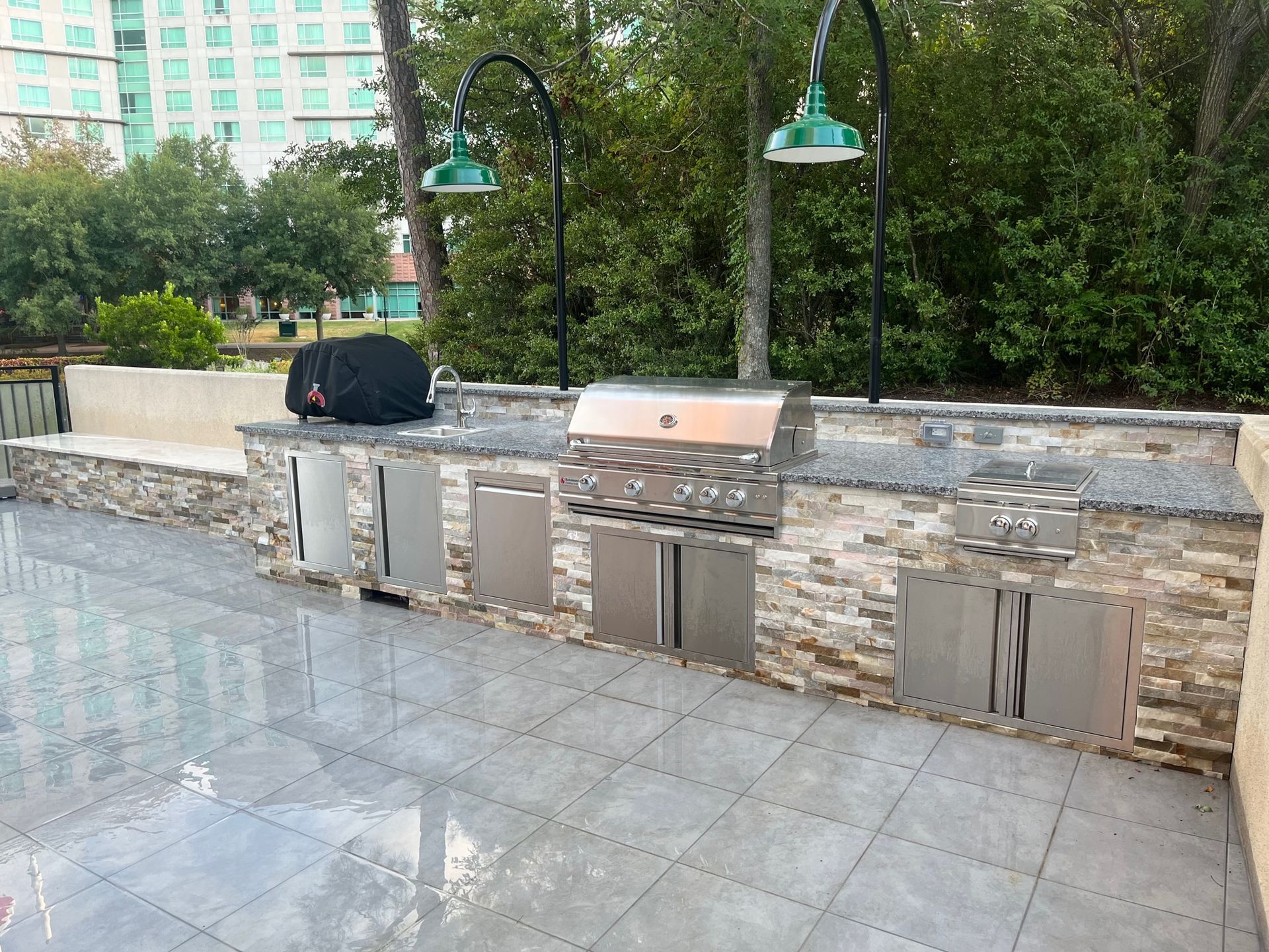 A large outdoor kitchen with a grill and cabinets