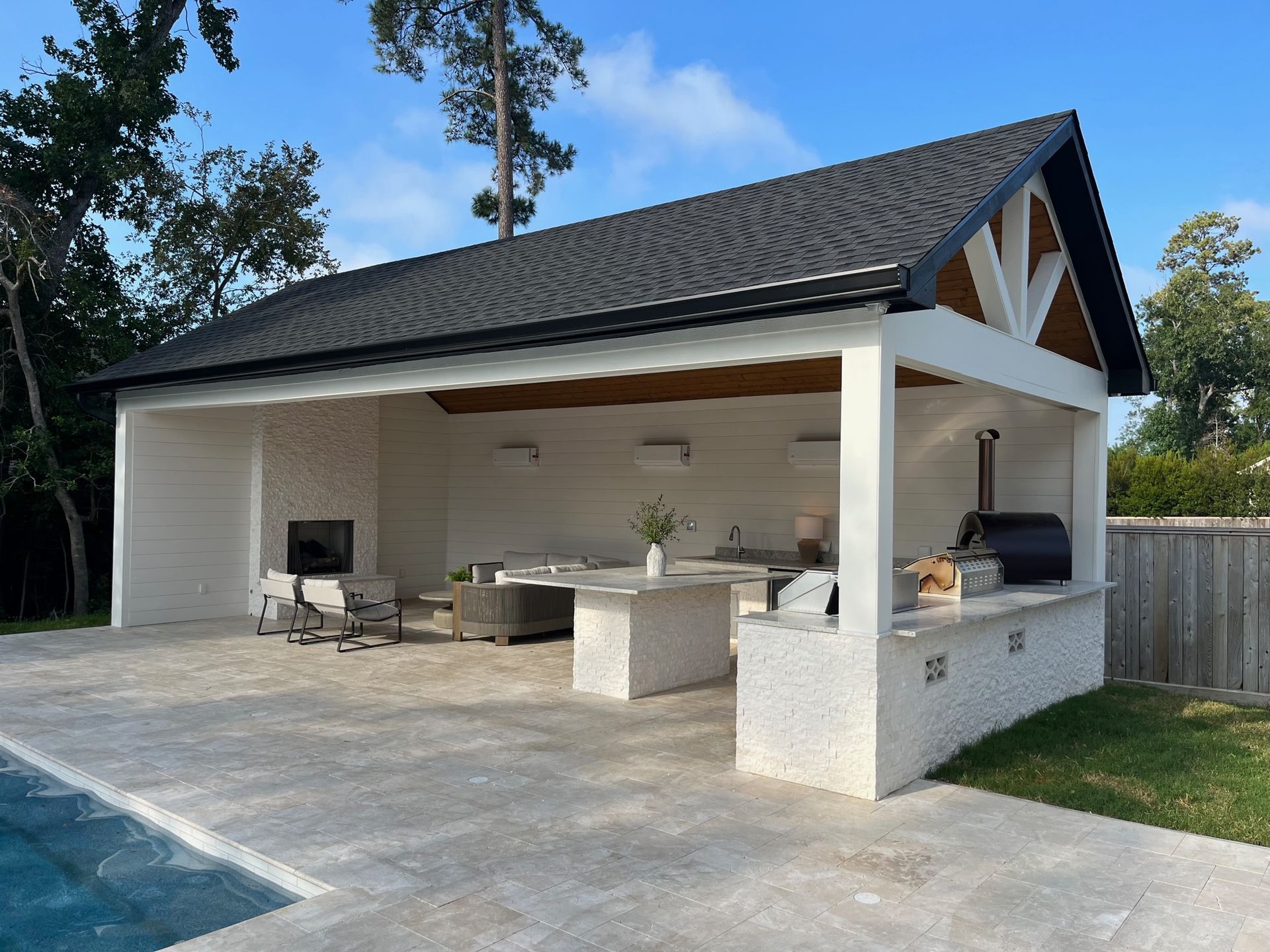 A white building with a black roof is next to a swimming pool