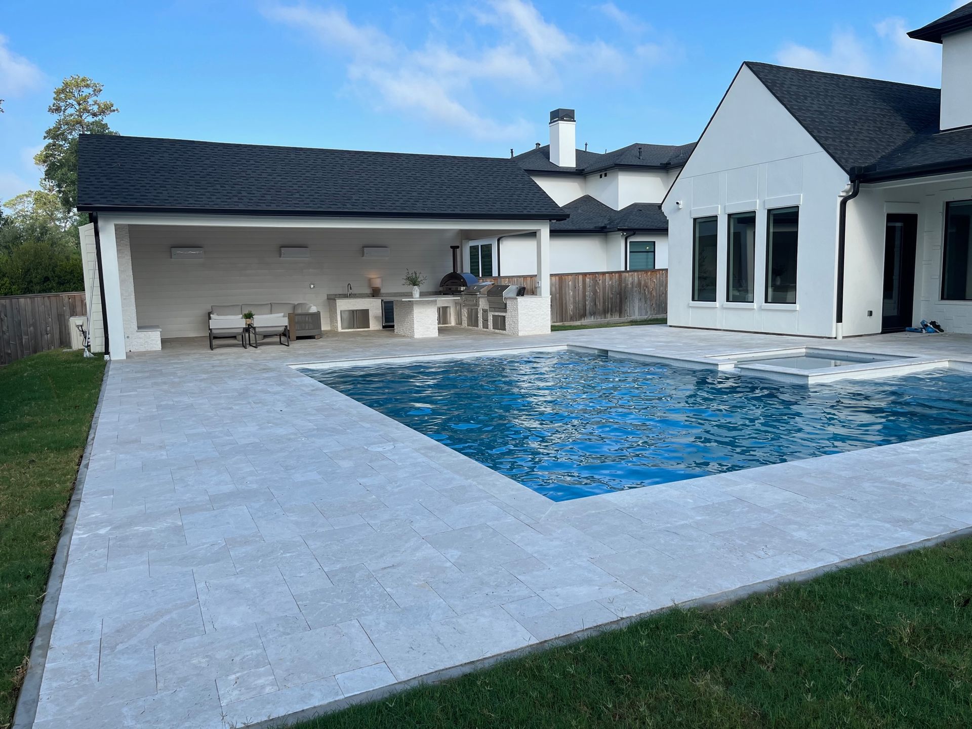 A large swimming pool is in the backyard of a house.