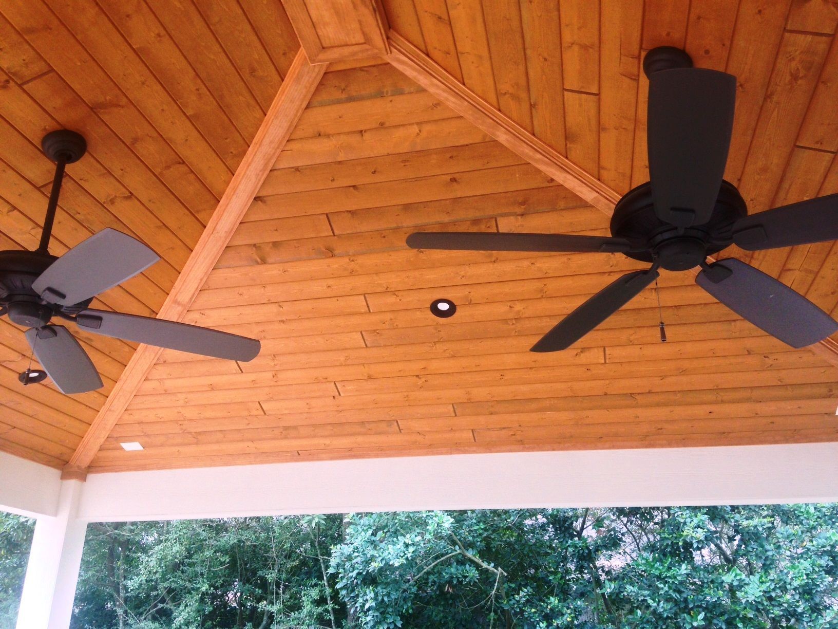 Two ceiling fans are hanging from a wooden ceiling