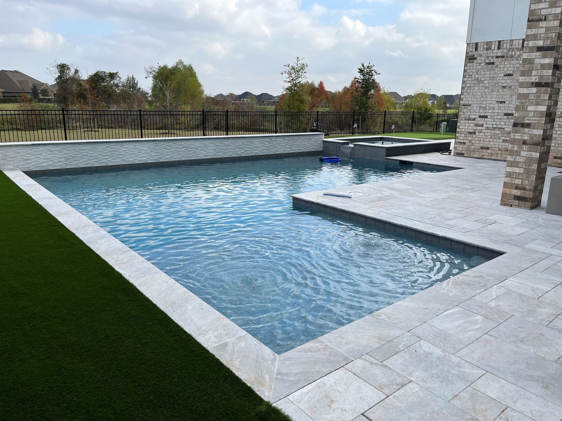 There is a large swimming pool in the backyard of a house.