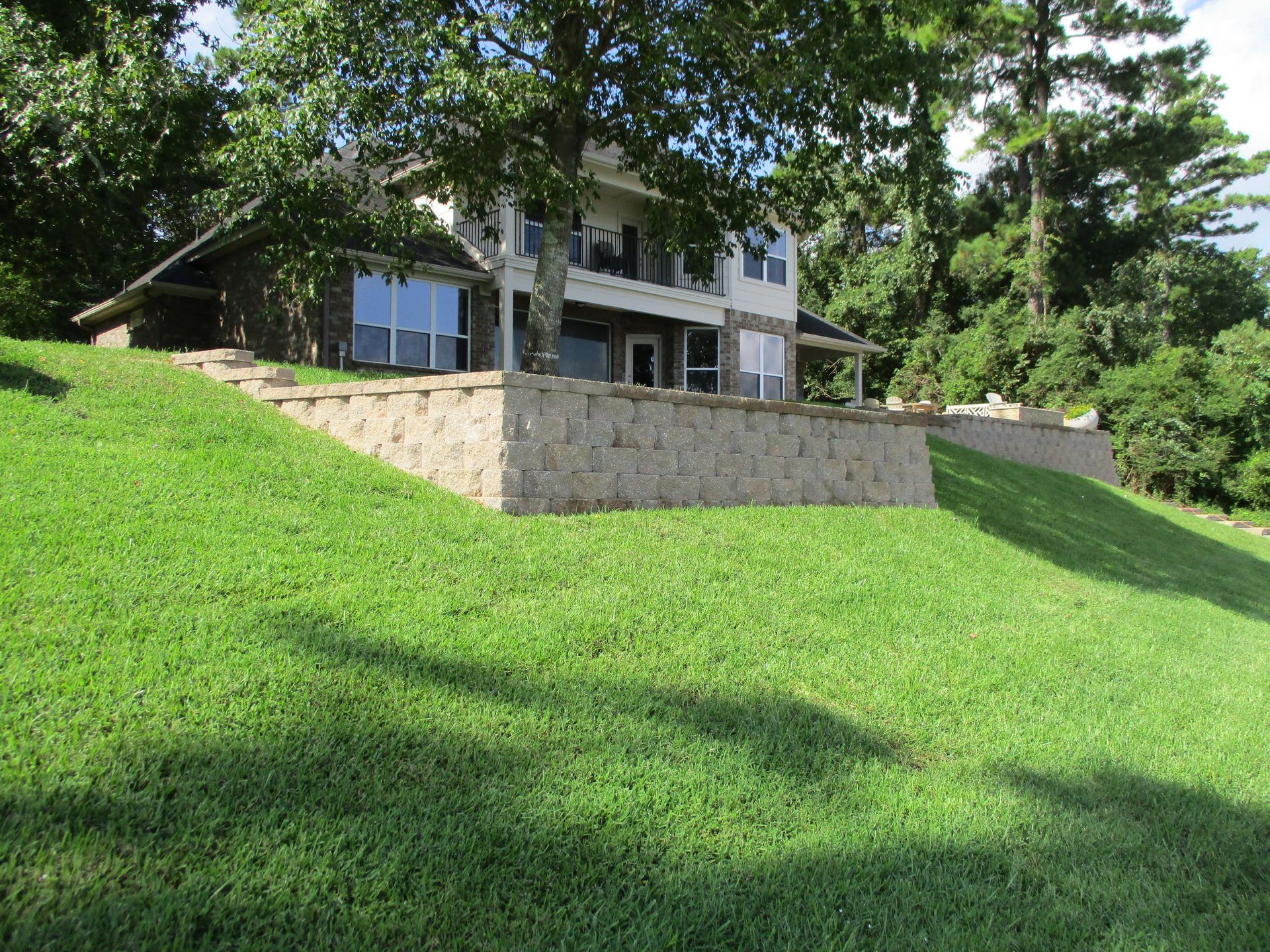 A large house is sitting on top of a lush green hill.
