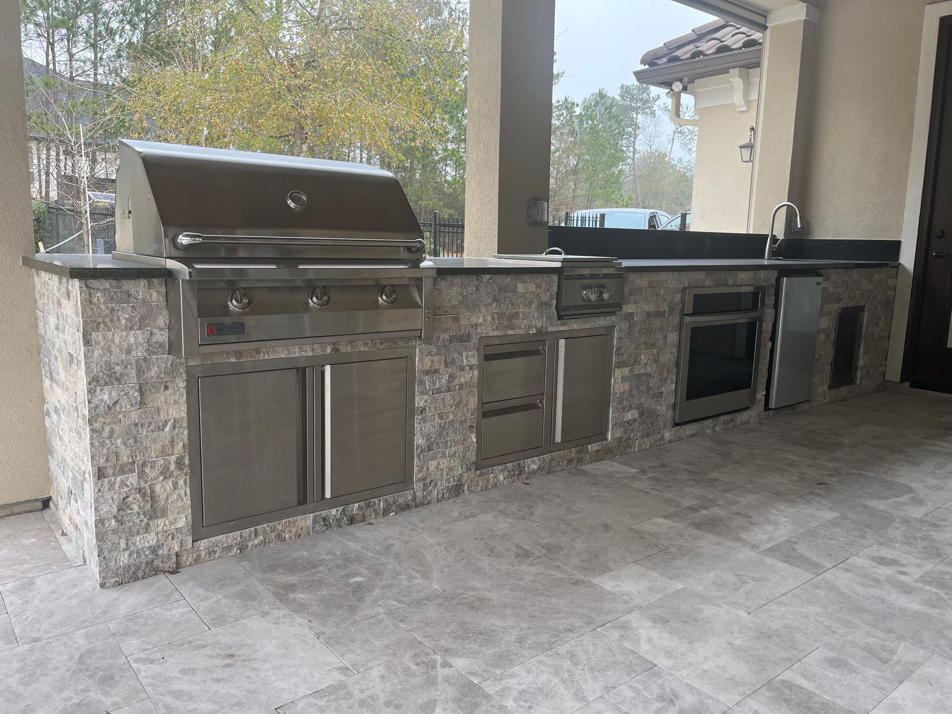 A large outdoor kitchen with a grill and a sink
