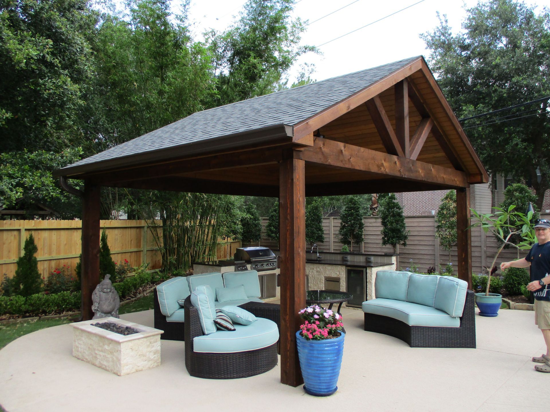 A man is standing in front of a pavilion with a fire pit