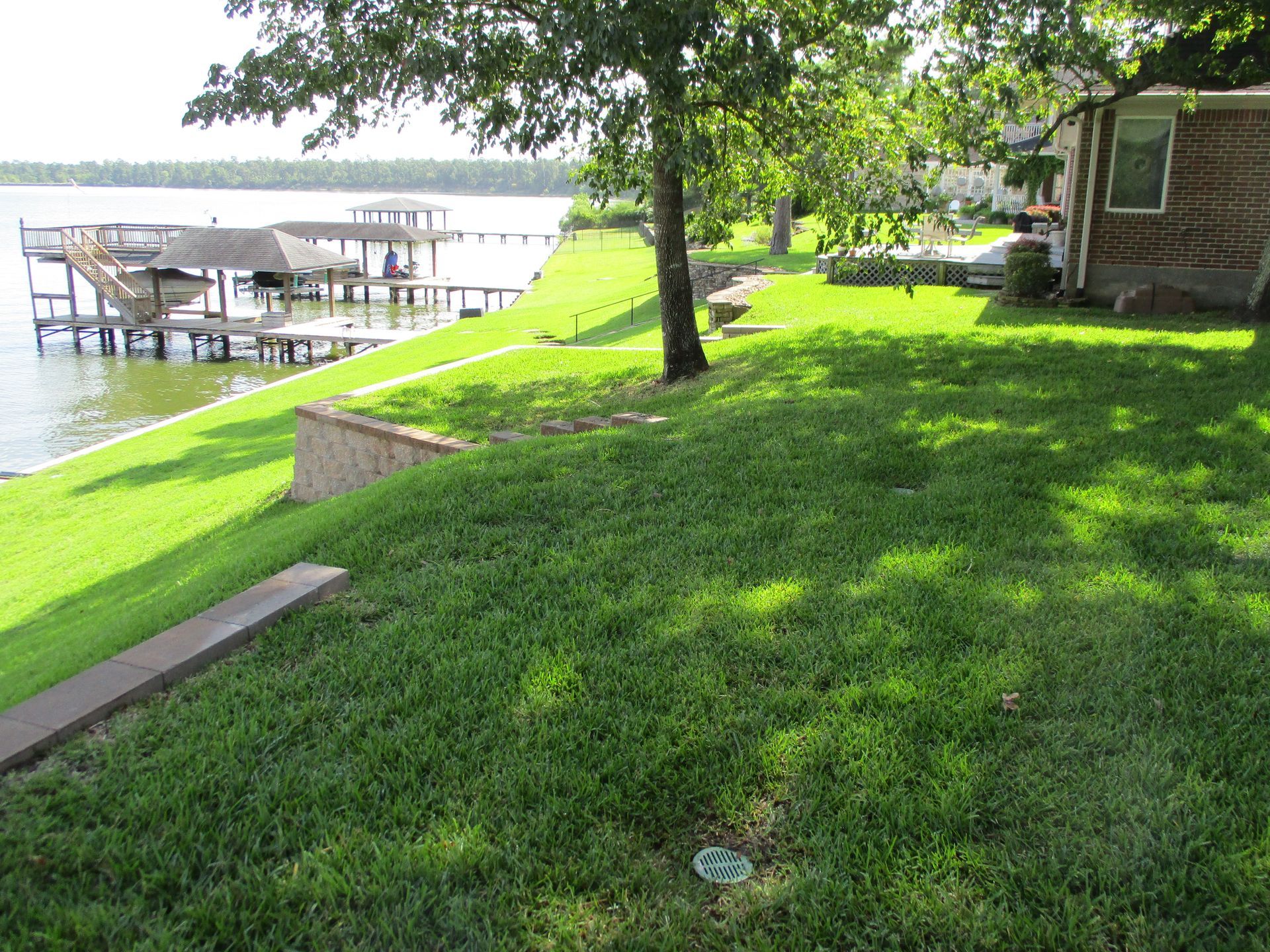A house is sitting on the shore of a lake next to a dock.