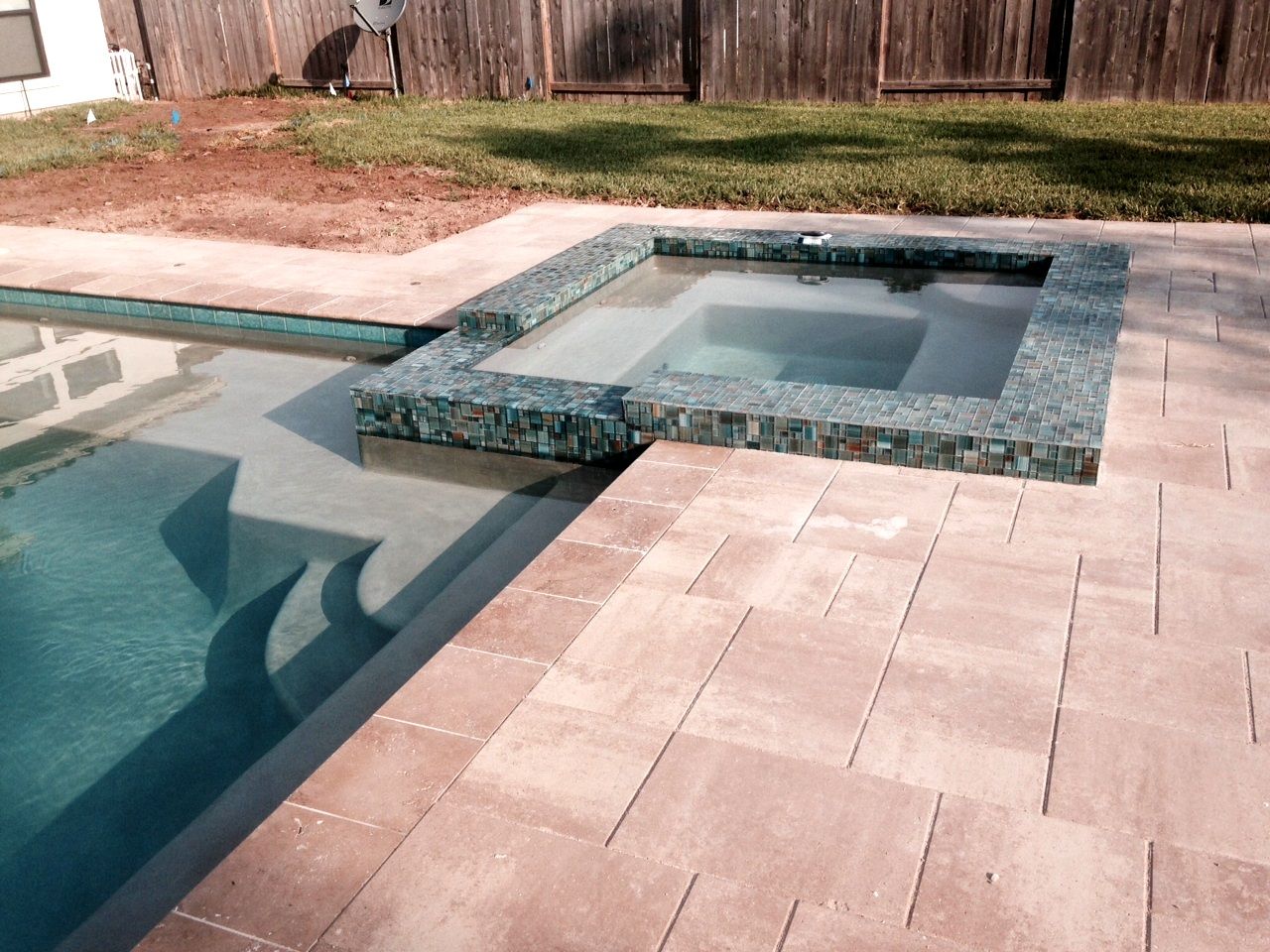 A swimming pool with a hot tub in the middle of it