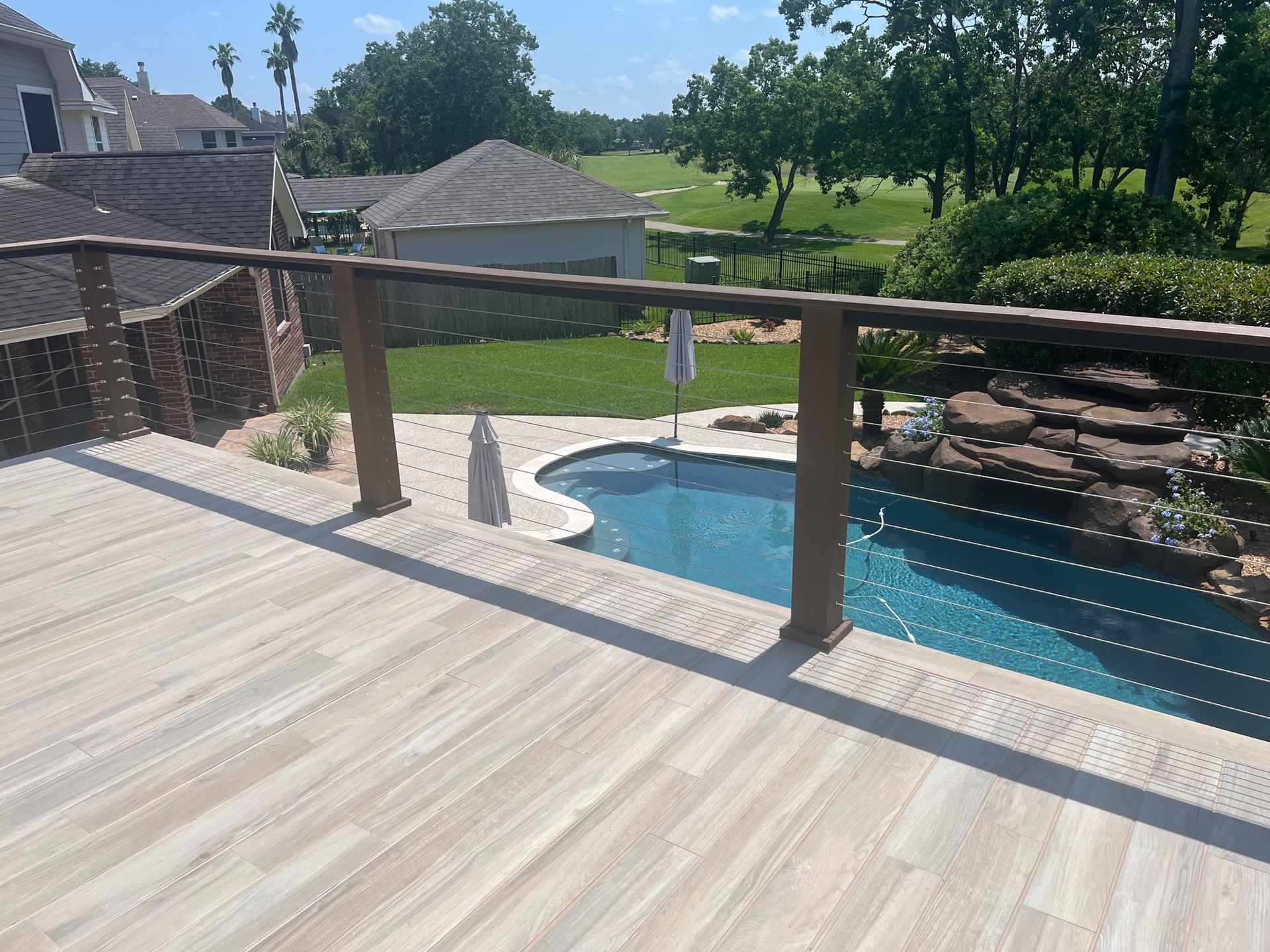 A deck with a view of a swimming pool and a golf course.